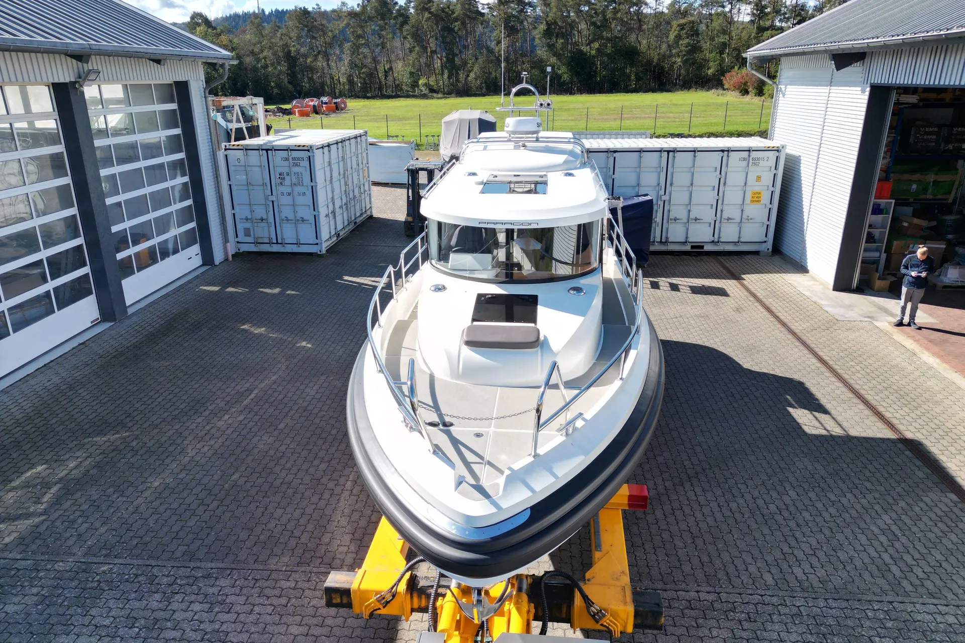 Paragon Yachts Paragon 31 — Bateau à moteur blanc vu de face sur une remorque, entre deux bâtiments.
