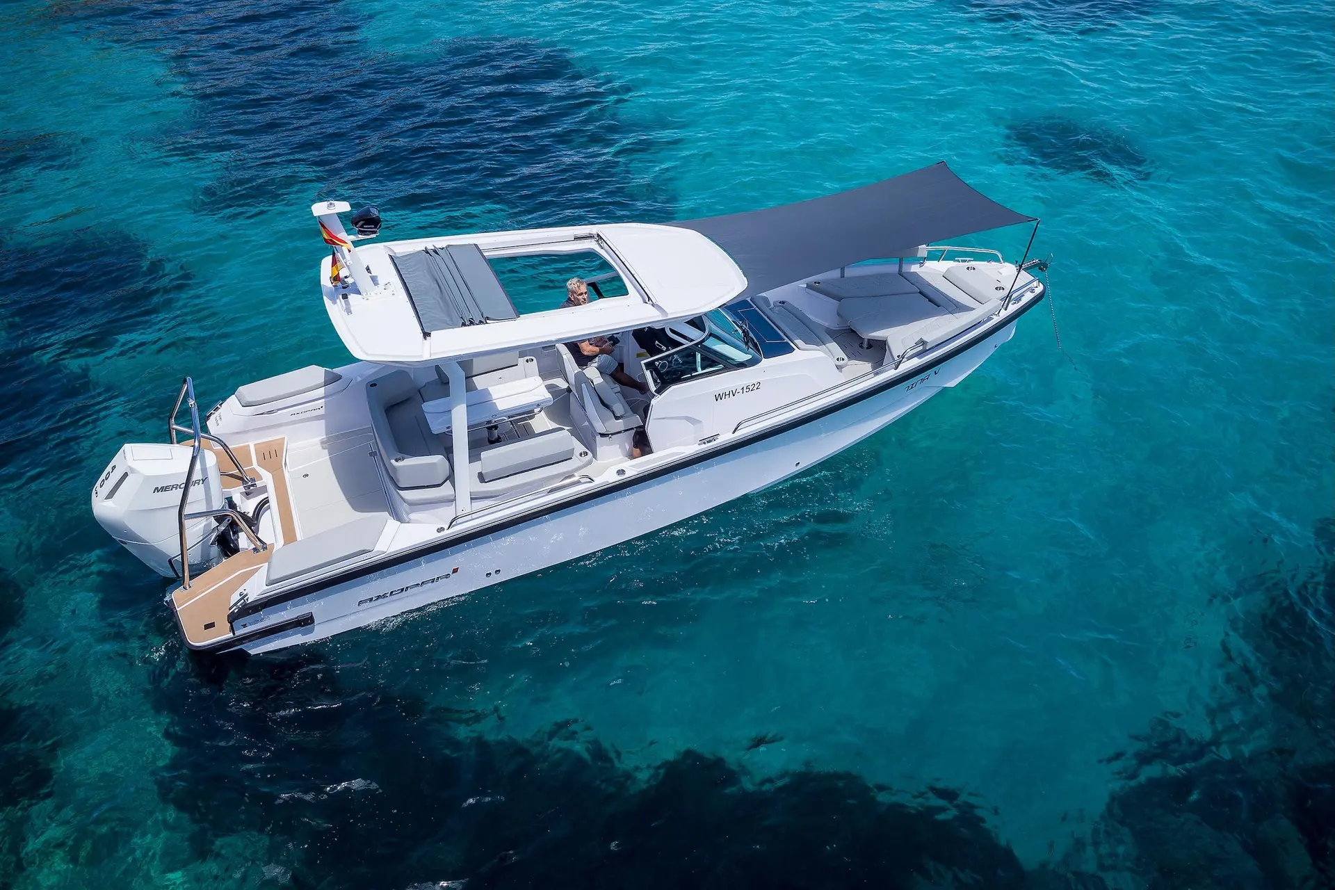 Axopar 29 Sun Top — Vue aérienne en trois-quarts d’un bateau blanc sur une eau turquoise.
