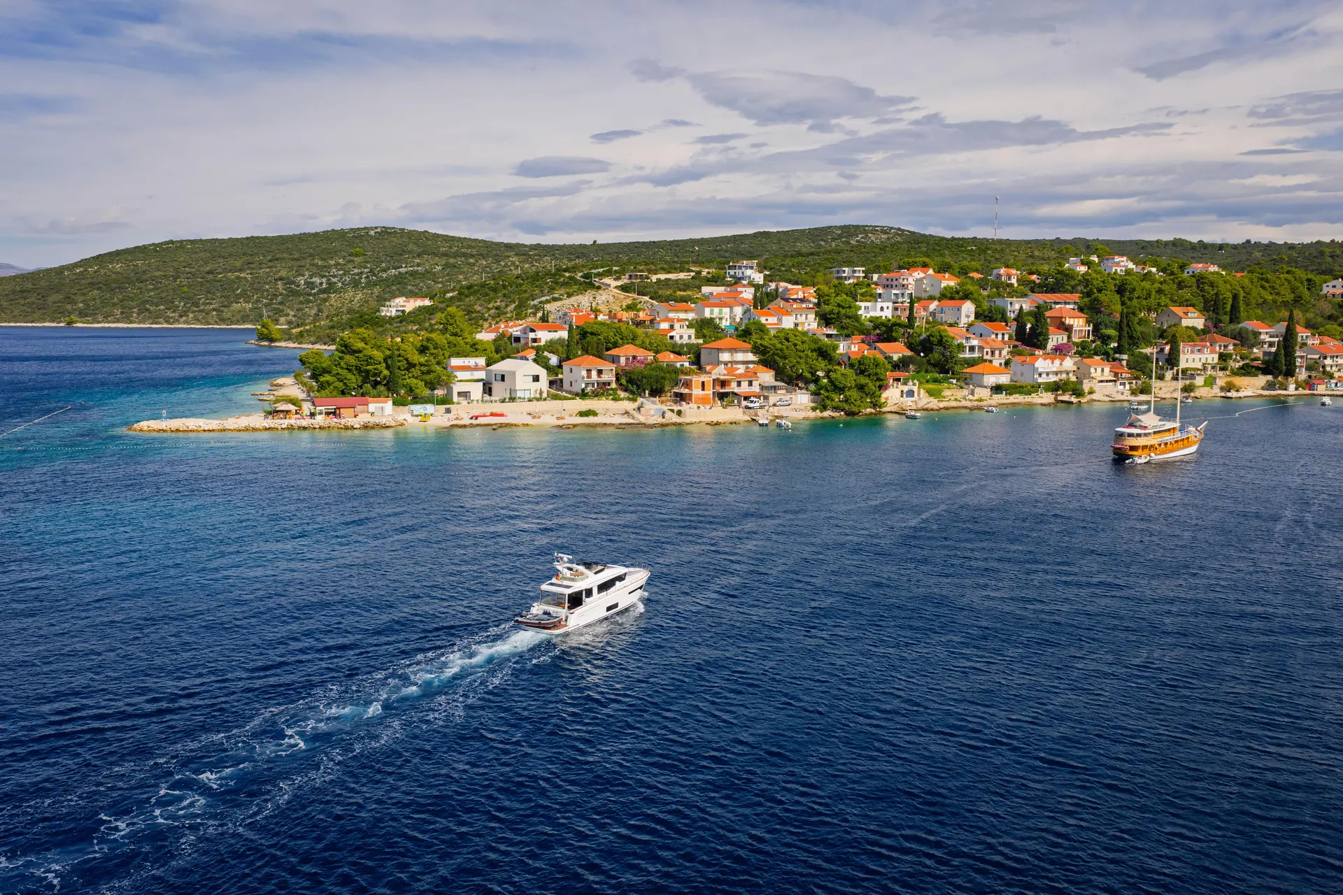 Nimbus 495 — Bateau à moteur naviguant devant un village côtier, vu du ciel.