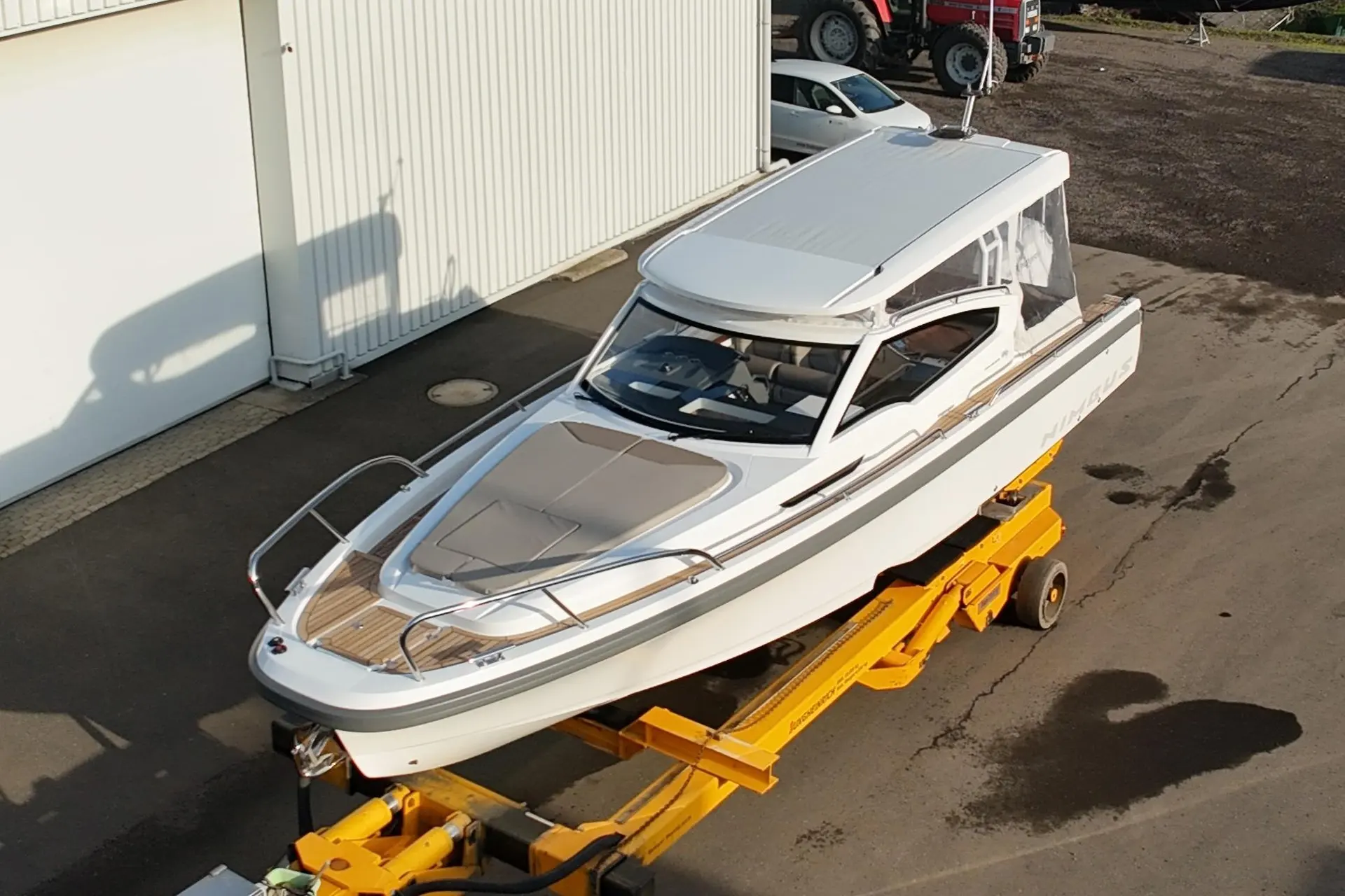 Nimbus W9 — Bateau blanc à cabine vu de trois quarts, posé sur une remorque devant un hangar.