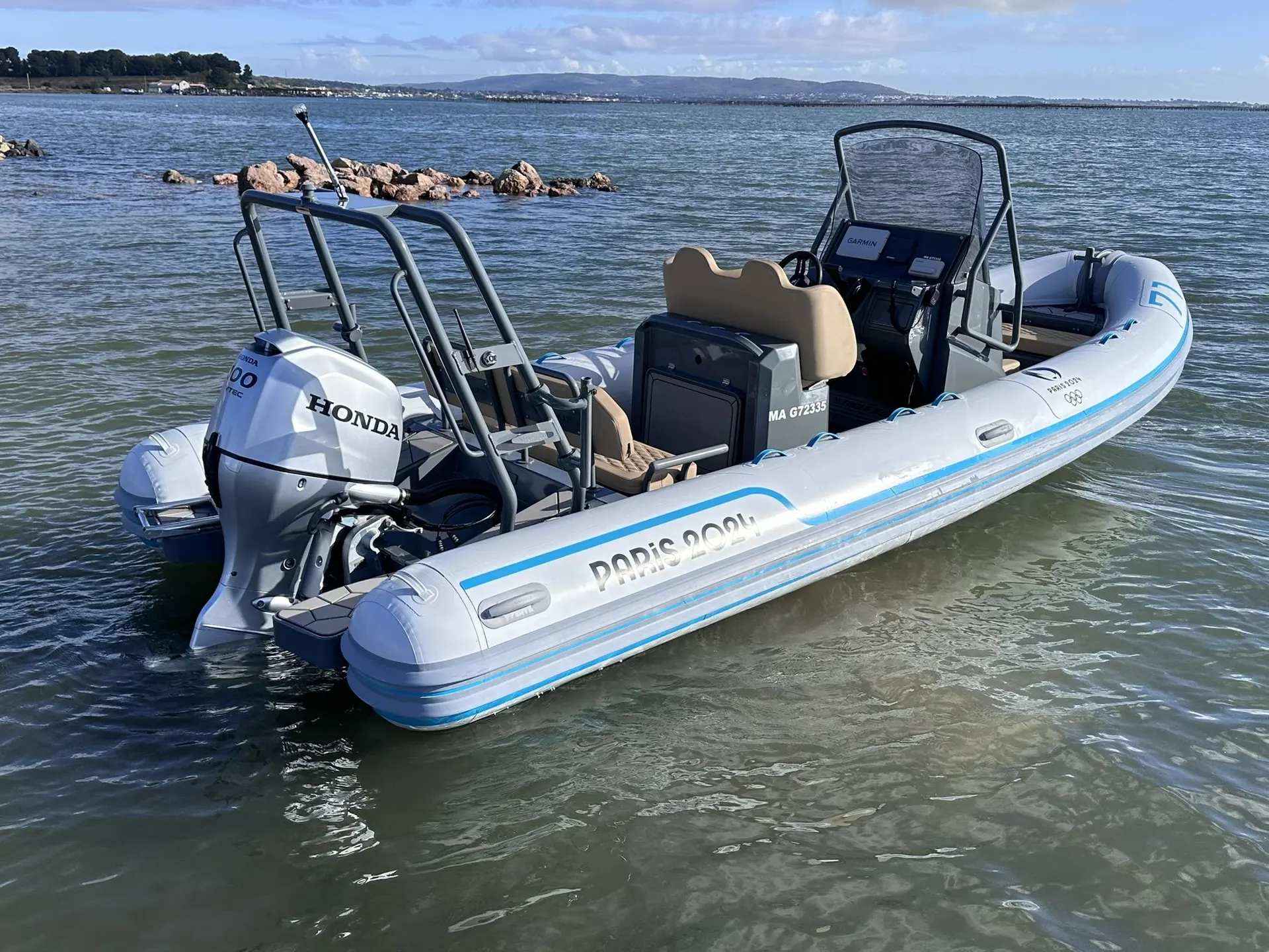 Highfield sport 600 JO — Semi-rigide blanc photographié sur l’eau, avec console centrale et moteur hors-bord.