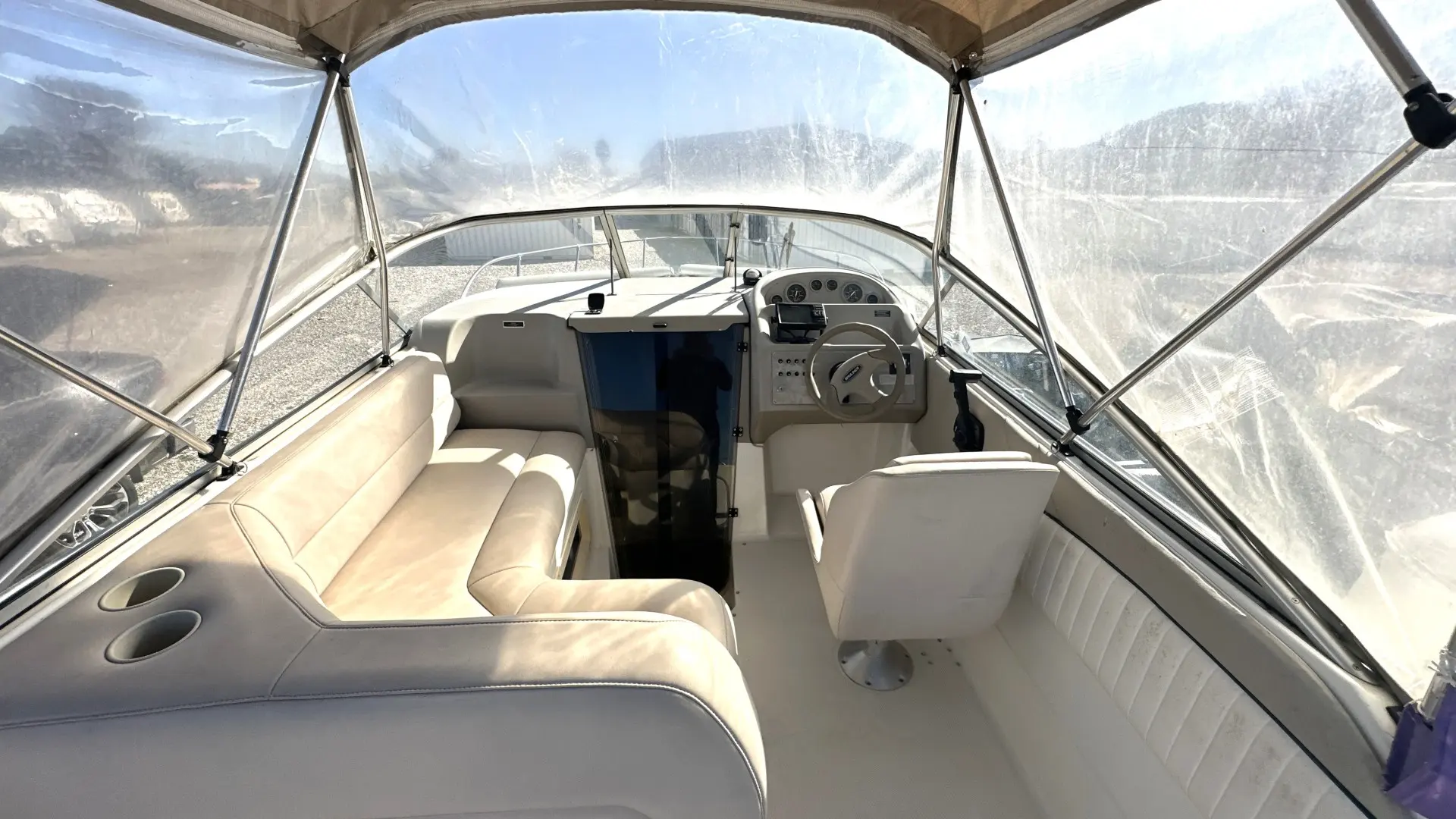 Bayliner Cierra 2355 Sunbridge — Vue du cockpit et du poste de pilotage d’un bateau, sous taud transparent.