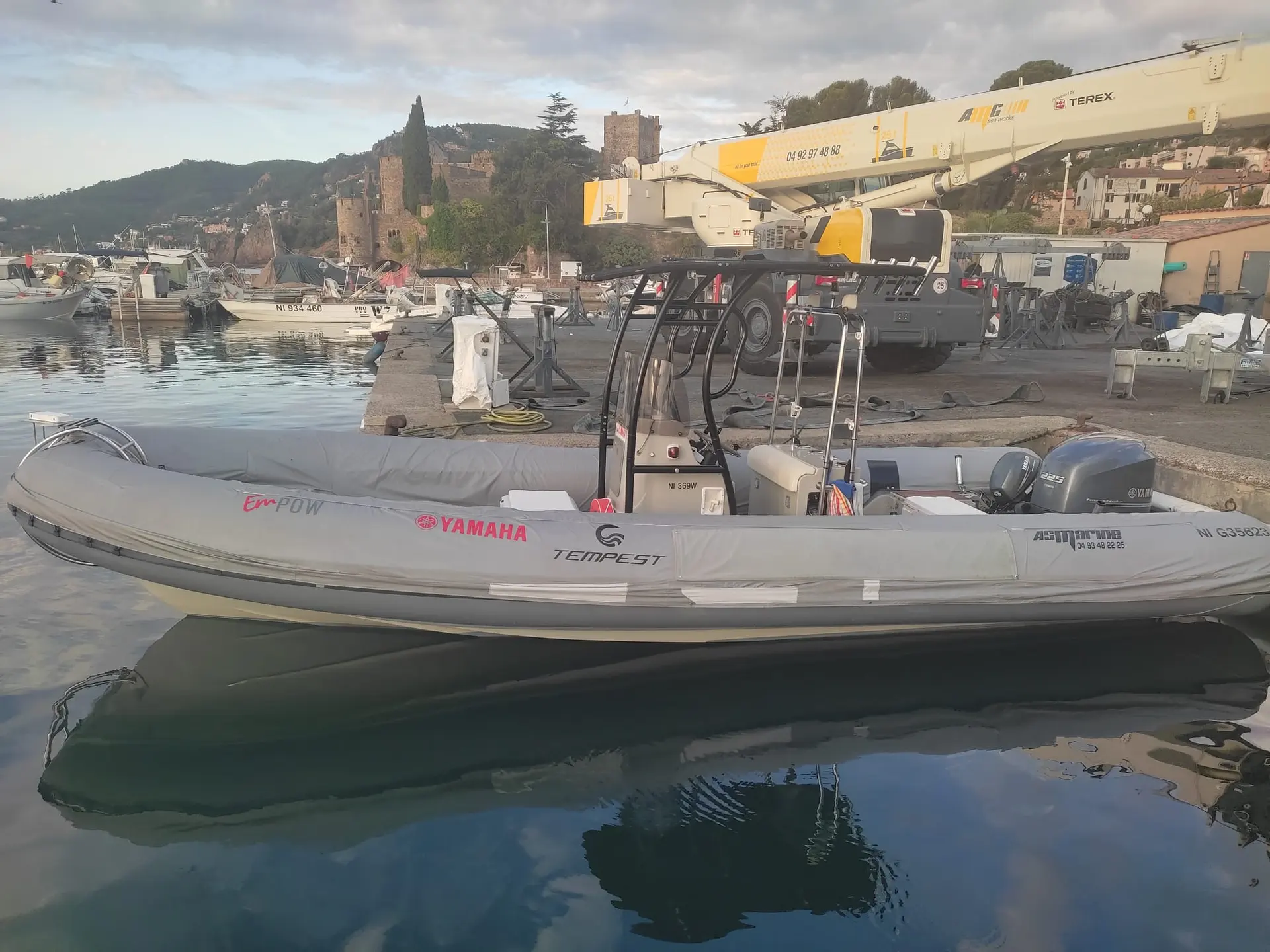 Capelli 750 Work — Bateau pneumatique gris amarré dans un port, sous une grue mobile.