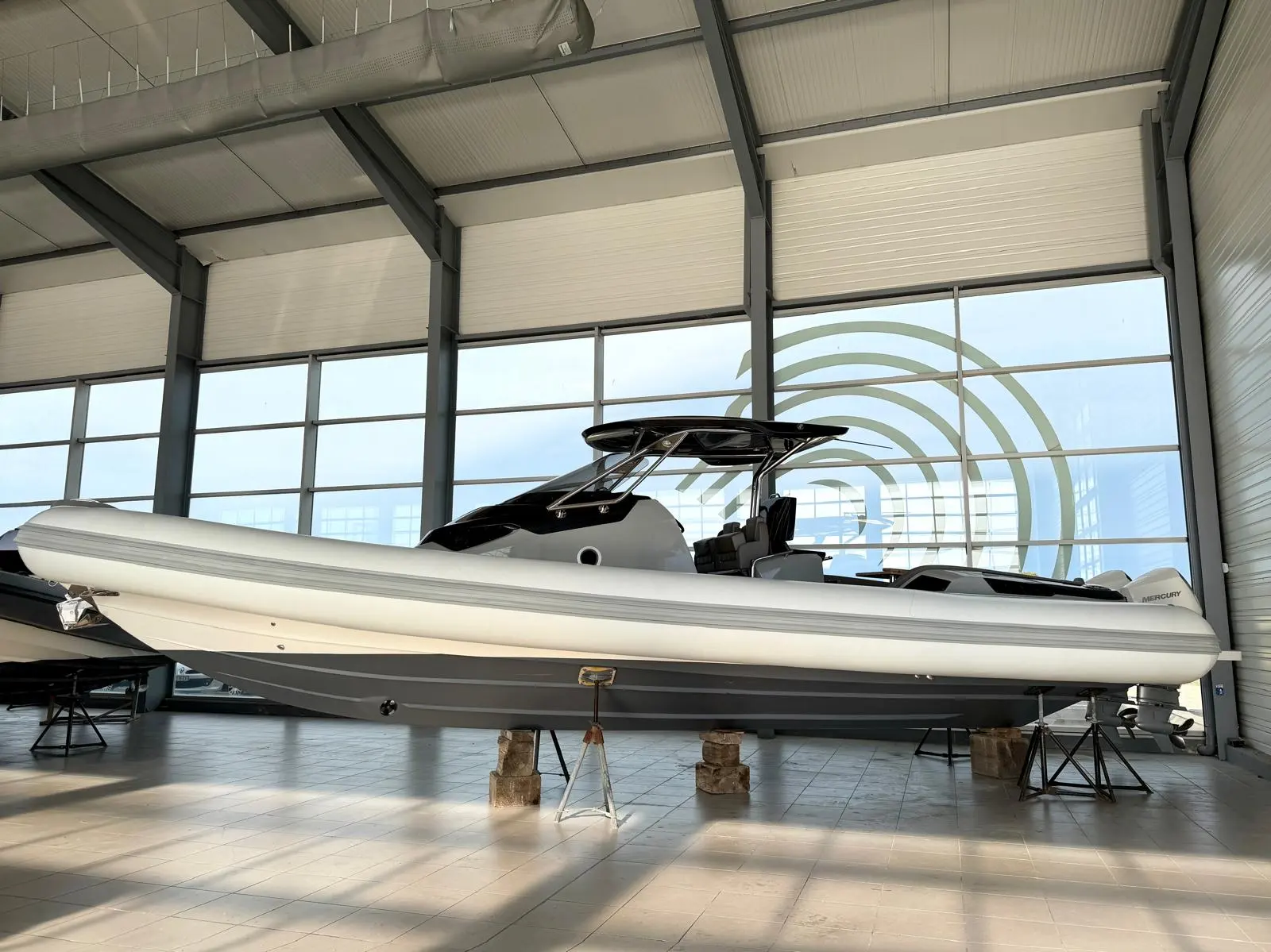 Sacs Strider 11 — Bateau semi-rigide blanc présenté sur bers dans un showroom, vue latérale.