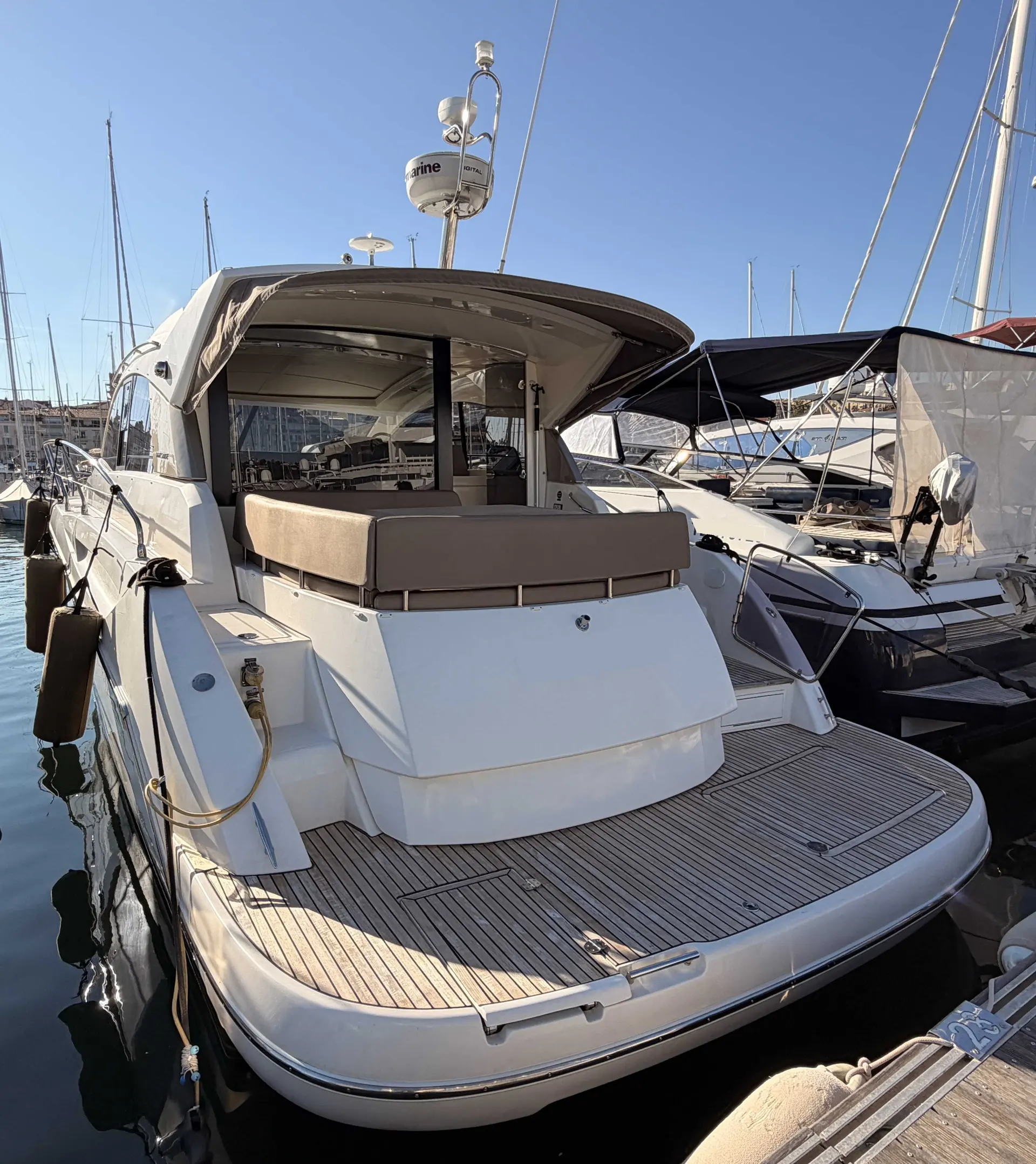 Prestige Yachts 440 S — Vue arrière d’un bateau à moteur amarré, avec cockpit couvert et grande plateforme de bain.