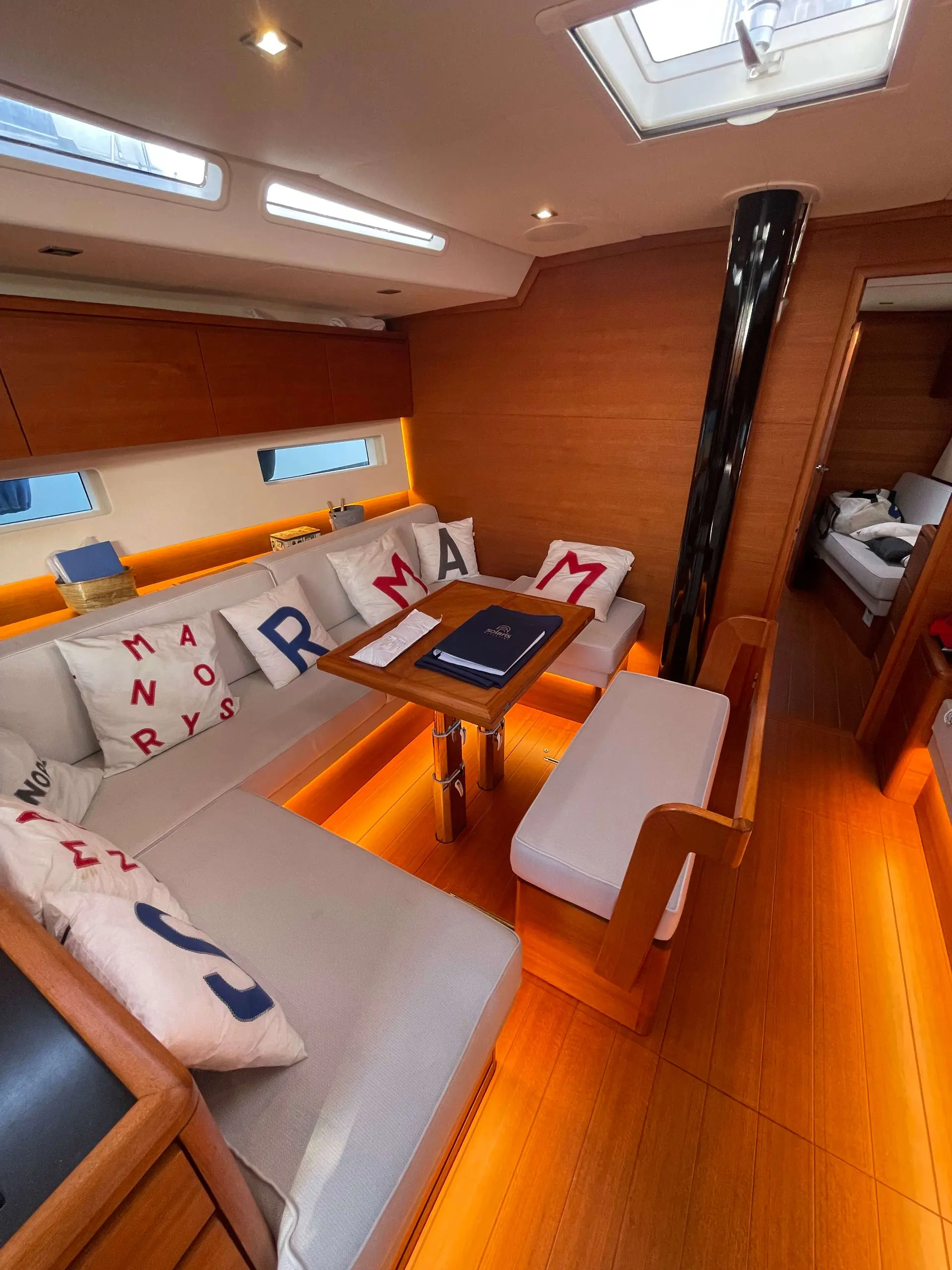 Solaris 55 — Salon intérieur en bois avec banquettes, table et éclairage encastré.
