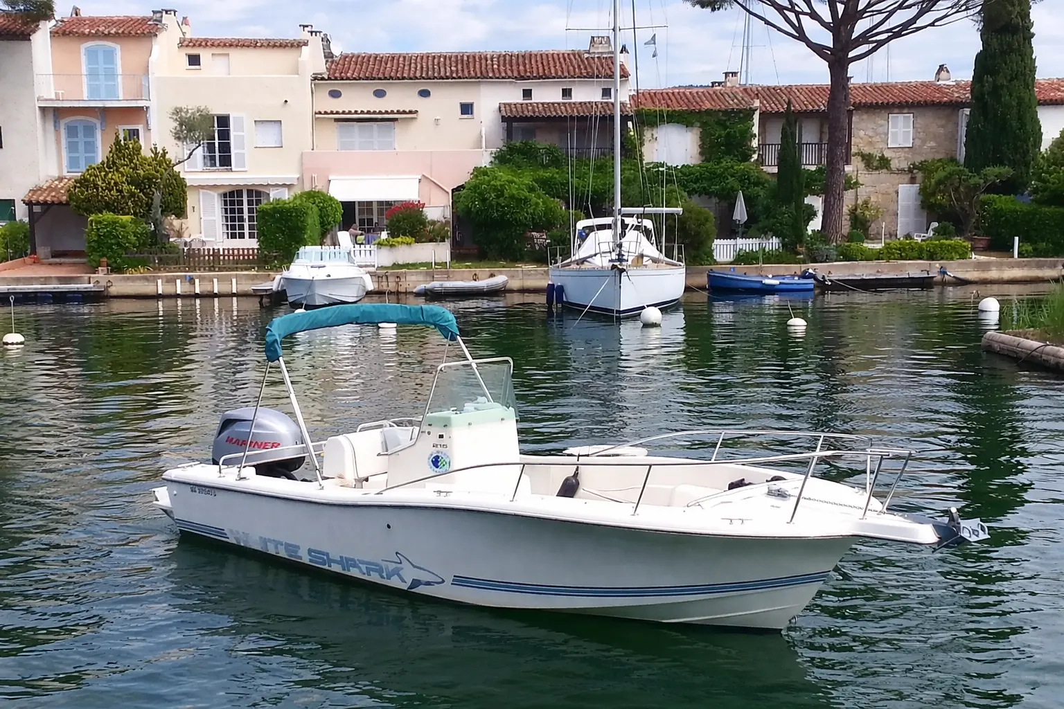 White Shark 215 — Bateau à moteur blanc photographié de trois quarts dans un port résidentiel.