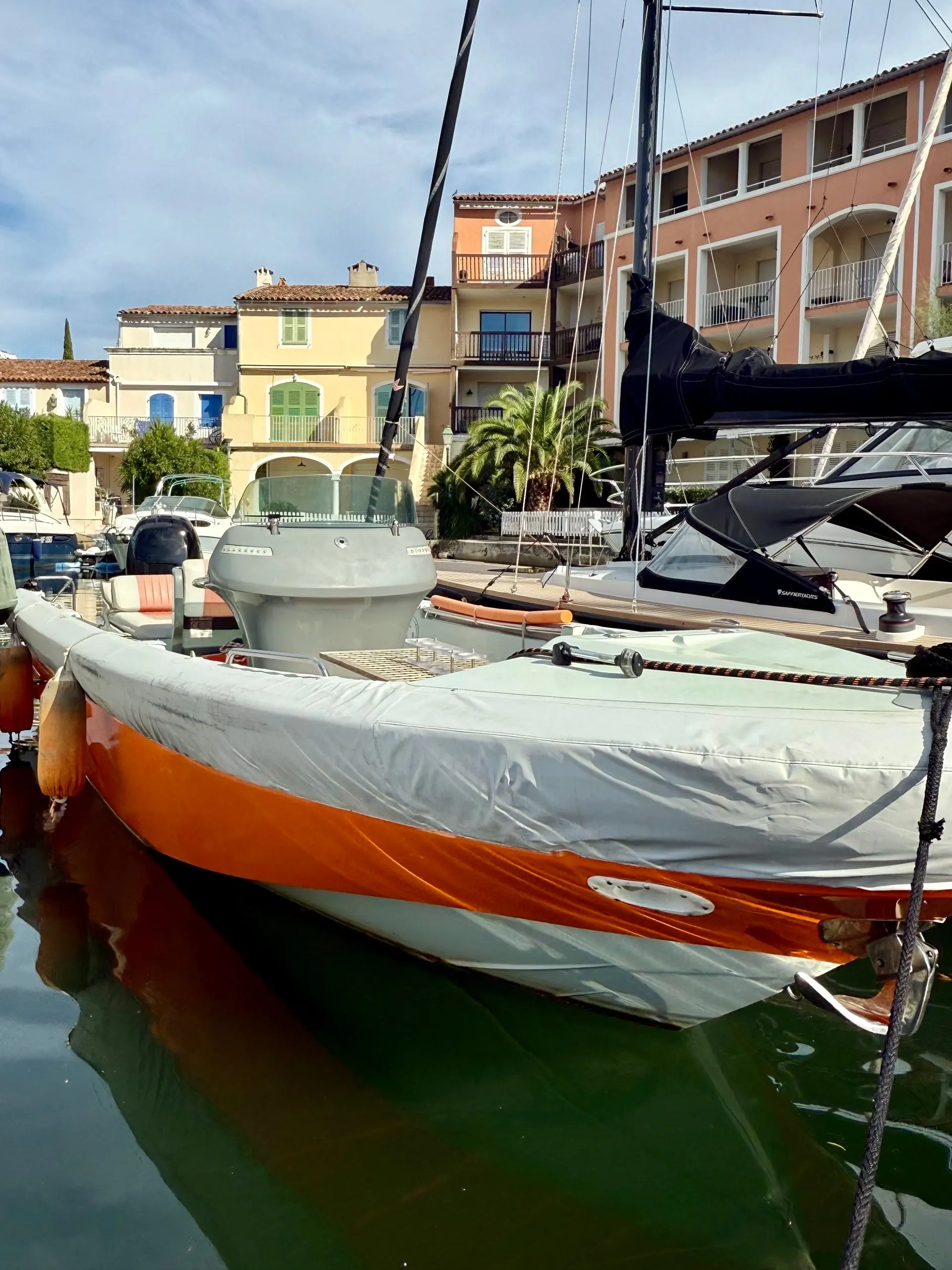 Expression 25 — Bateau orange amarré dans un port, vu de côté parmi d’autres embarcations.