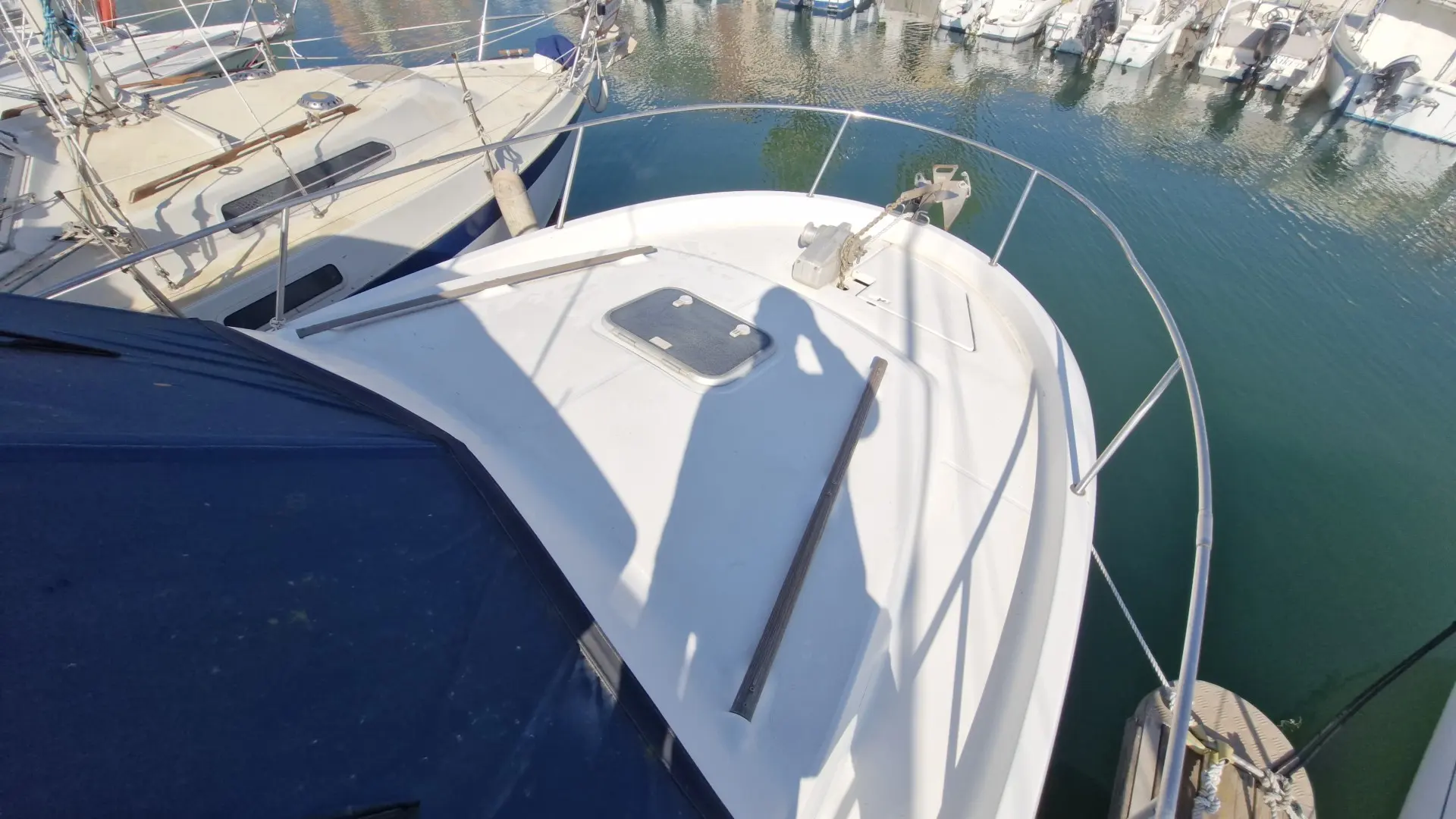 Beneteau Antares 755 — Vue plongeante sur la proue et le pont avant d’un bateau amarré au port.