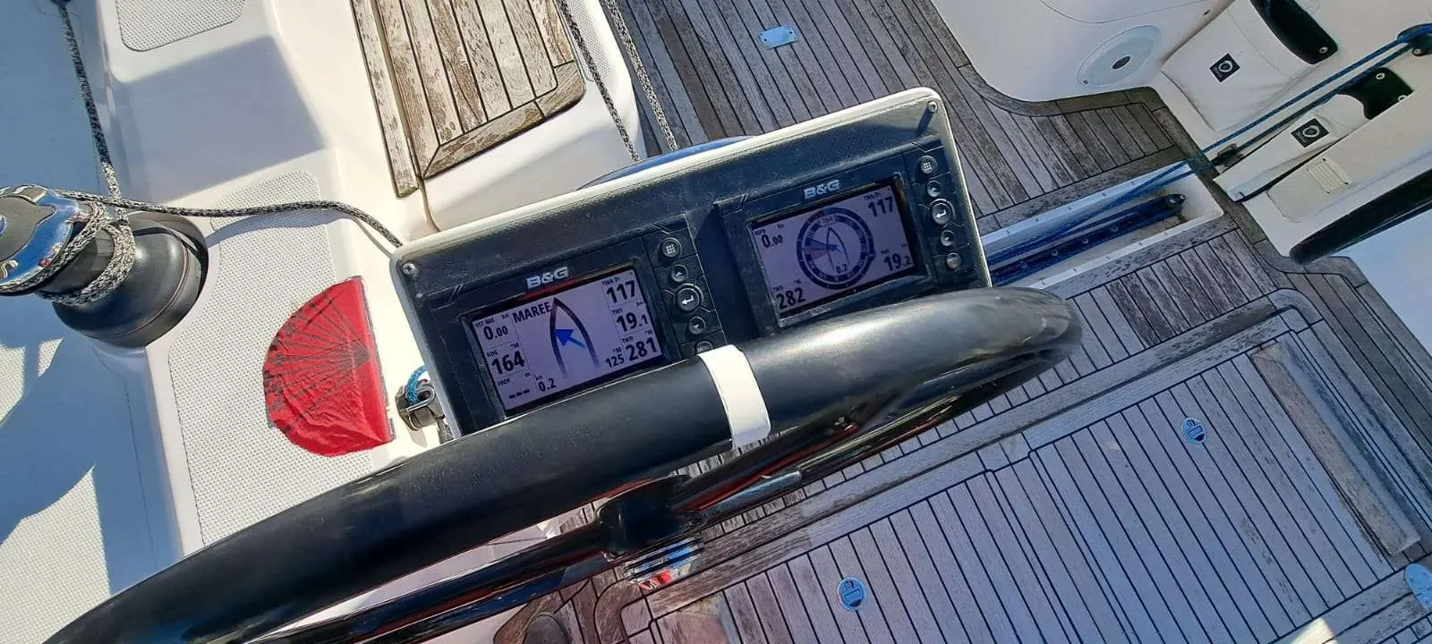 Salona 380 — Vue rapprochée du tableau de navigation et du pont en teck du voilier.