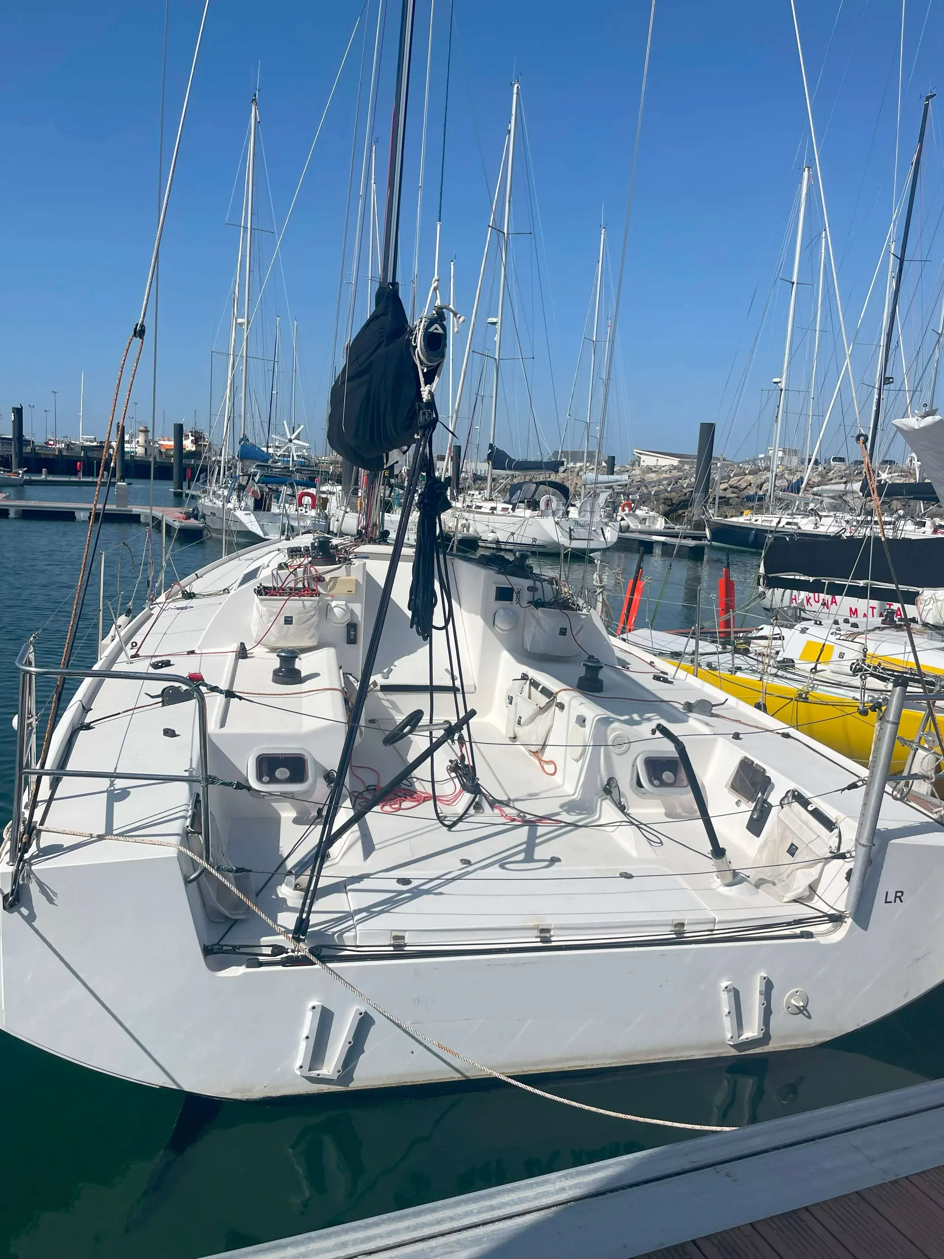 Pogo Structures Pogo 30 — Voilier blanc vu depuis l’arrière, amarré dans une marina par temps ensoleillé.