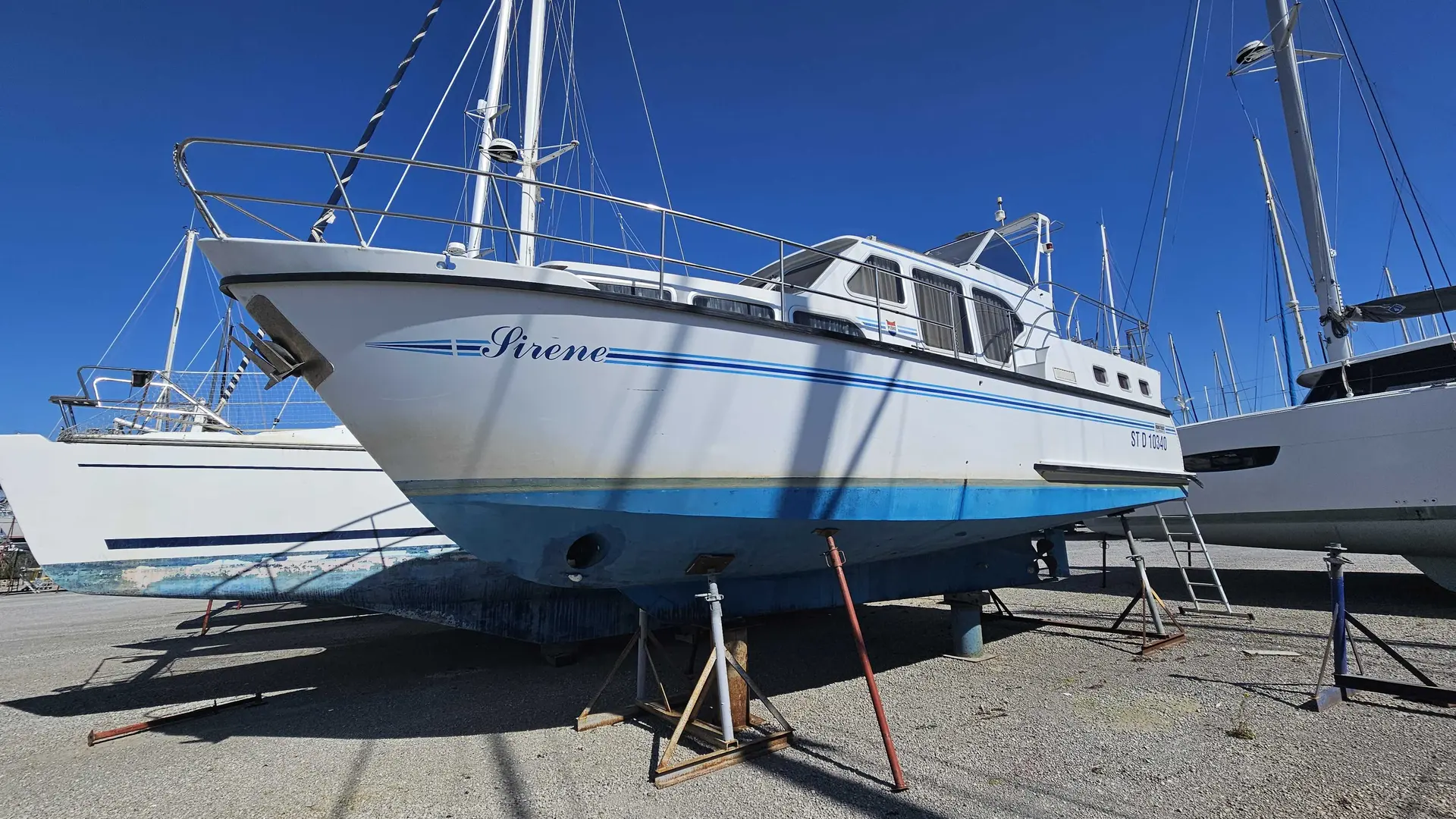 Pedro Boat Skiron 35 — Voilier blanc et bleu nommé Sirene, photographié à terre dans un chantier naval.