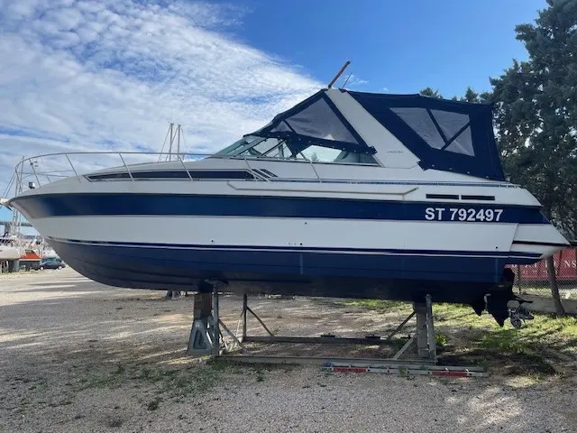 Carver 30 Allegra — Bateau à moteur blanc et bleu présenté à terre sur un ber, vu de profil bâbord.