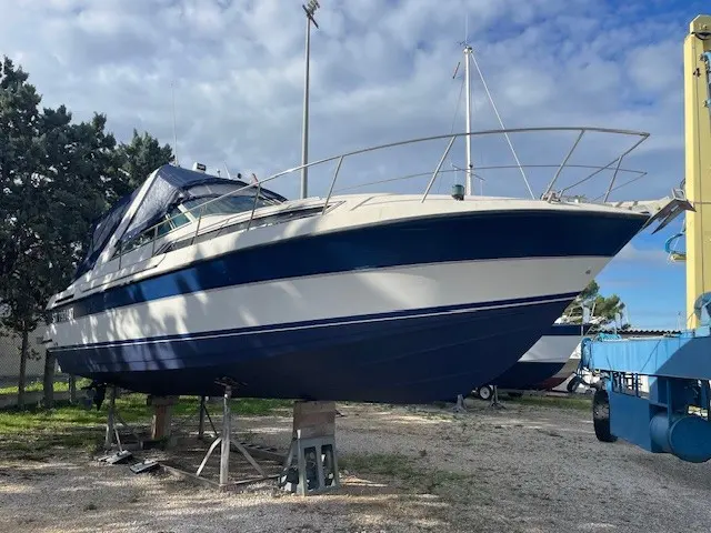 Carver 30 Allegra — Bateau à moteur bleu et blanc posé sur berceaux dans une aire à terre.