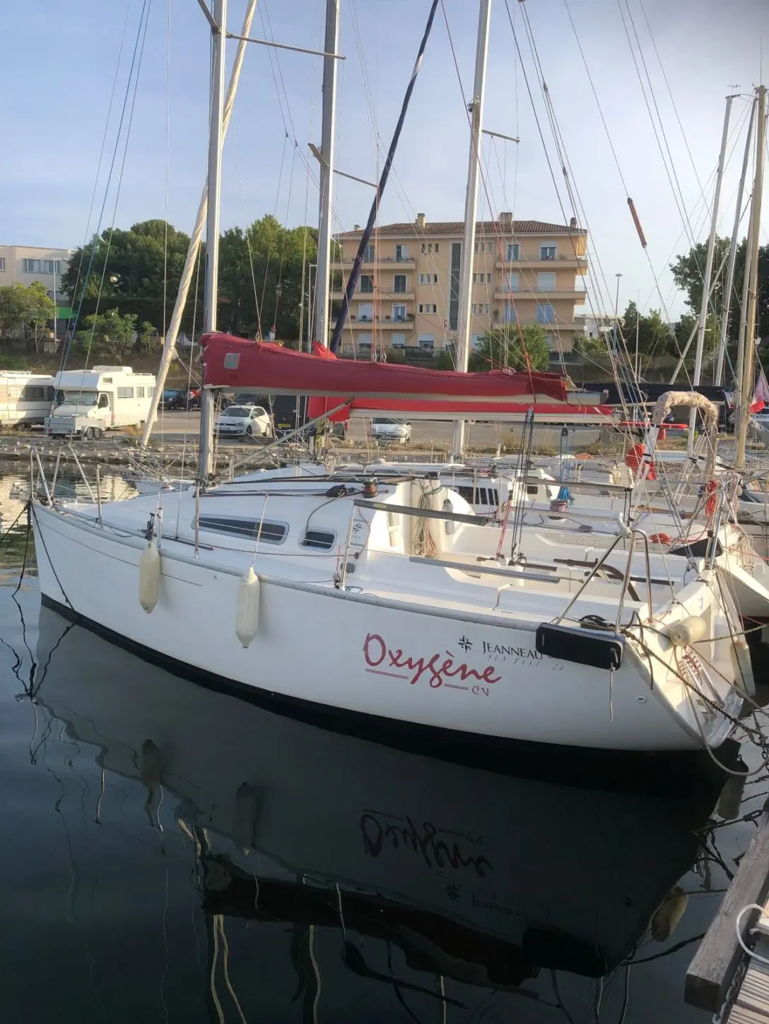 Jeanneau Sun Fast 26 — Voilier blanc amarré dans un port, vu de trois quarts entre d'autres bateaux.