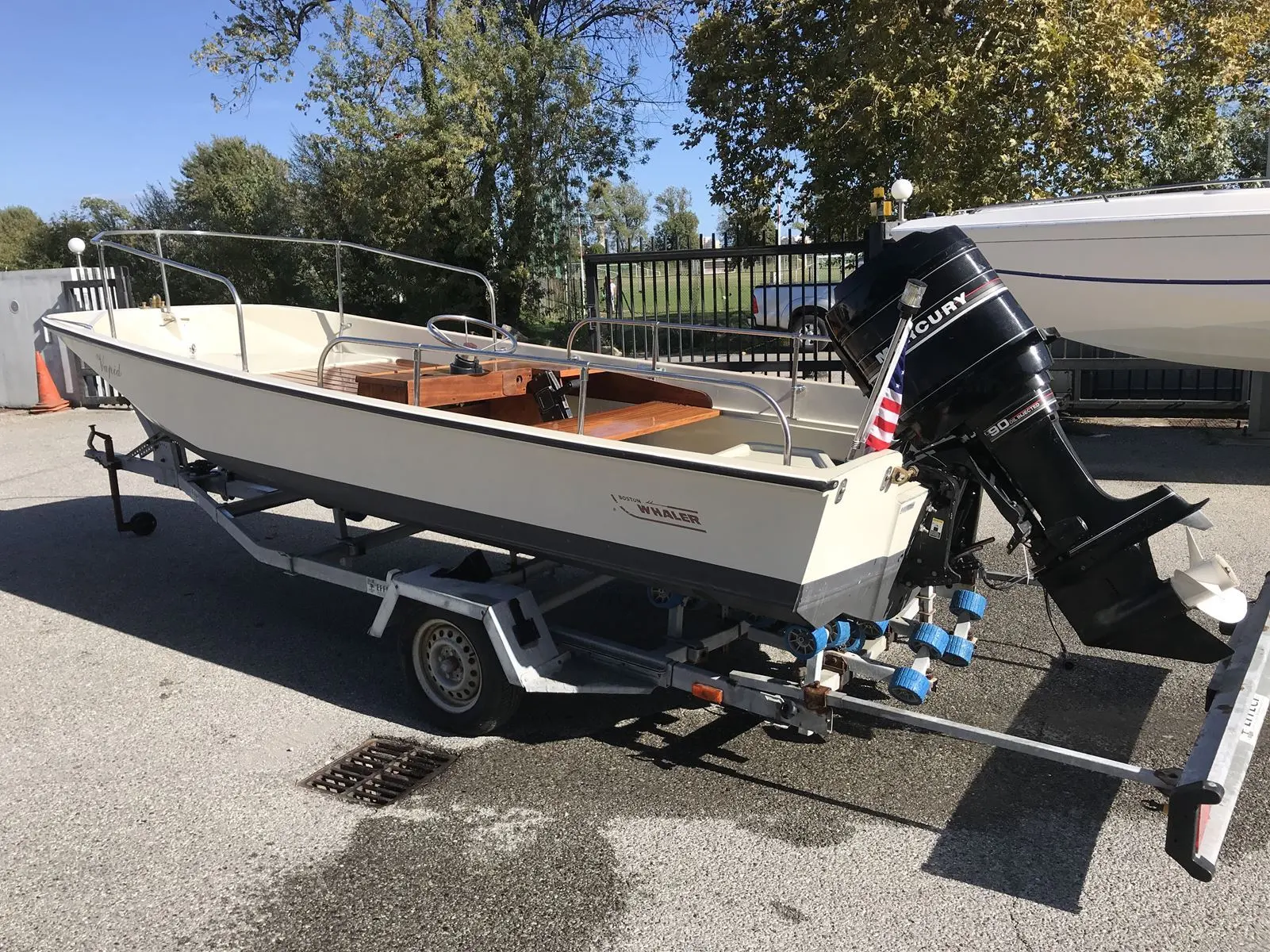 Boston Whaler 17 — Bateau à moteur blanc présenté sur sa remorque, vu de trois quarts arrière.