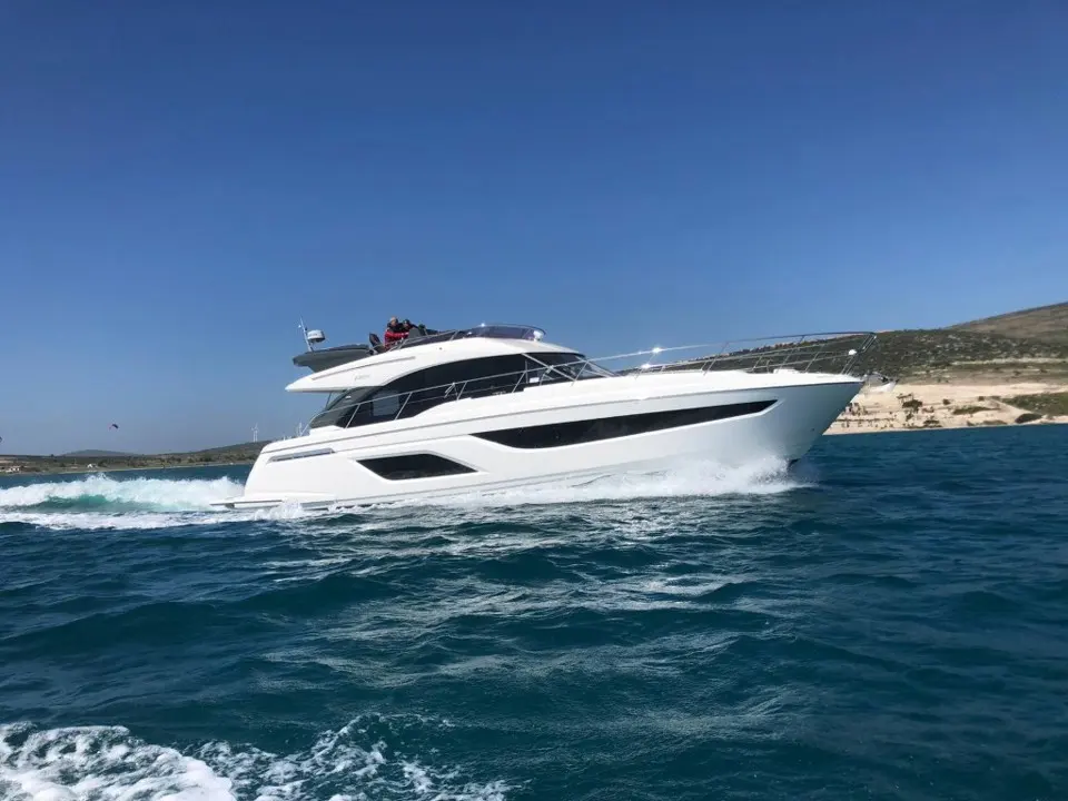 Bavaria R55 Fly — Vedette à moteur blanche naviguant au large, vue de profil sur une mer agitée.