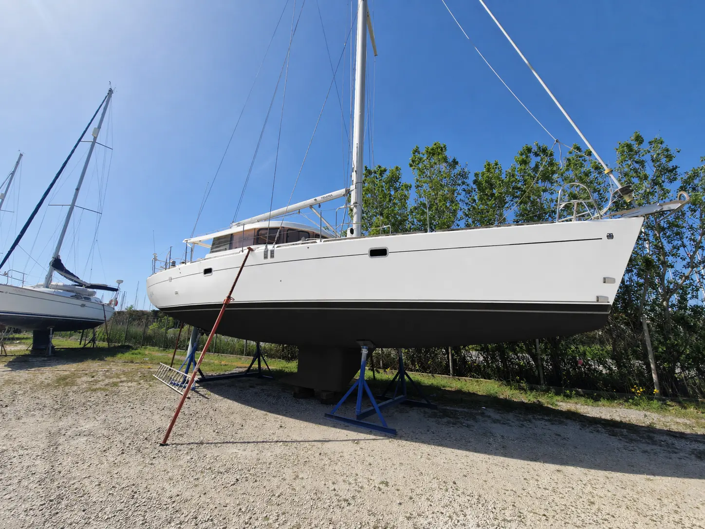 Dufour Atoll 43 — Voilier blanc photographié au sec, vu de profil tribord dans un chantier naval.