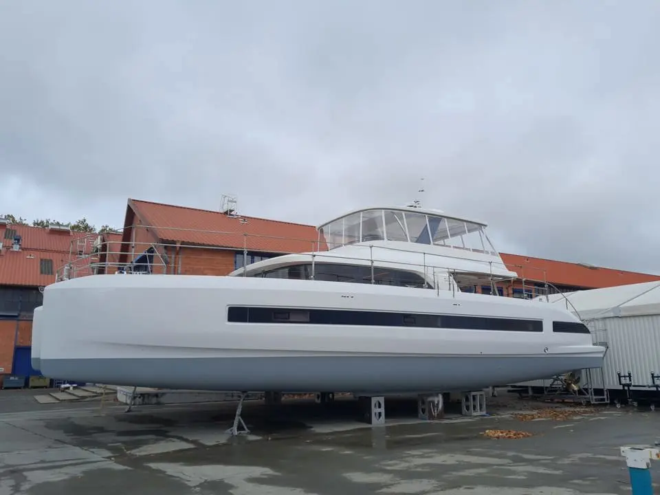 Lagoon Sixty 7 — Catamaran blanc vu de profil, posé sur bers dans une zone technique.