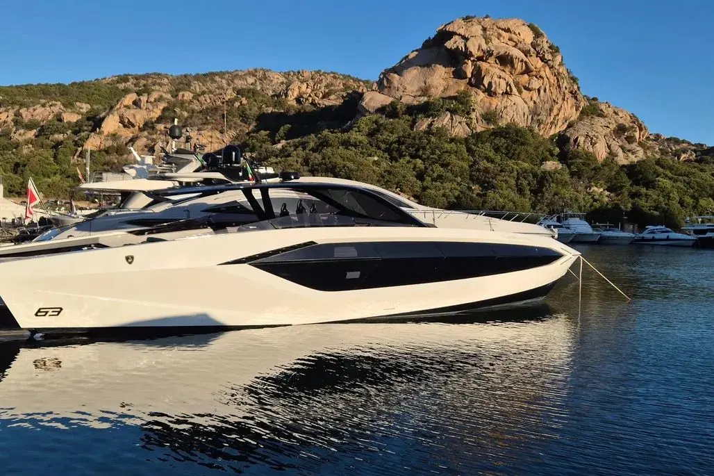 Tecnomar Lamborghini 63 — Bateau à moteur blanc amarré devant une côte rocheuse.