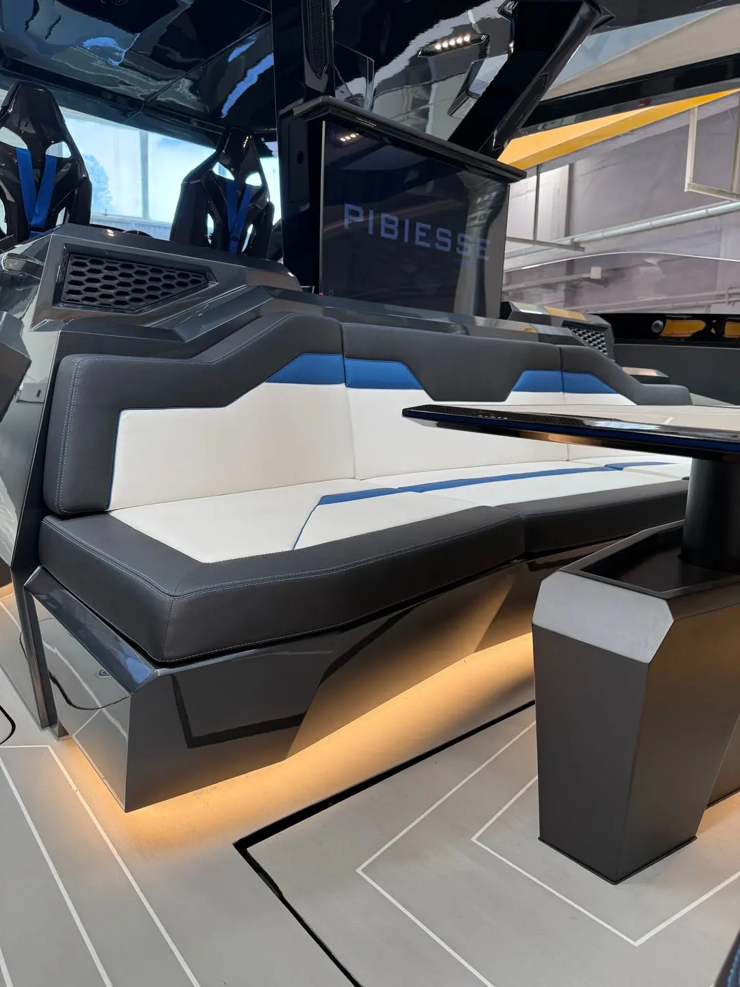 Tecnomar Lamborghini 63 — Banquette rembourrée bicolore dans le cockpit d’un bateau exposé en intérieur.