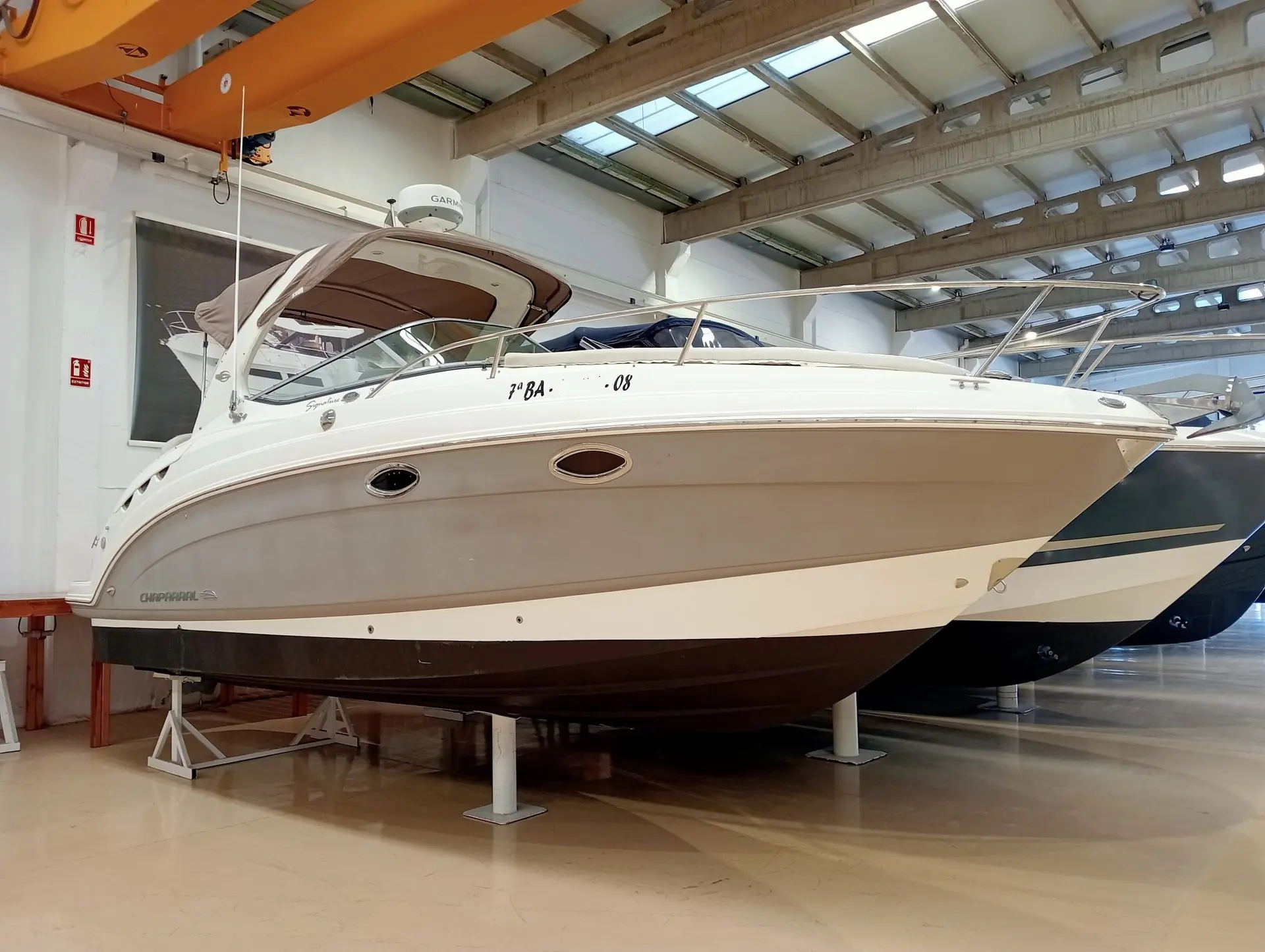 Chaparral Signature 250 — Bateau à moteur blanc présenté sur berceau dans un hall couvert.