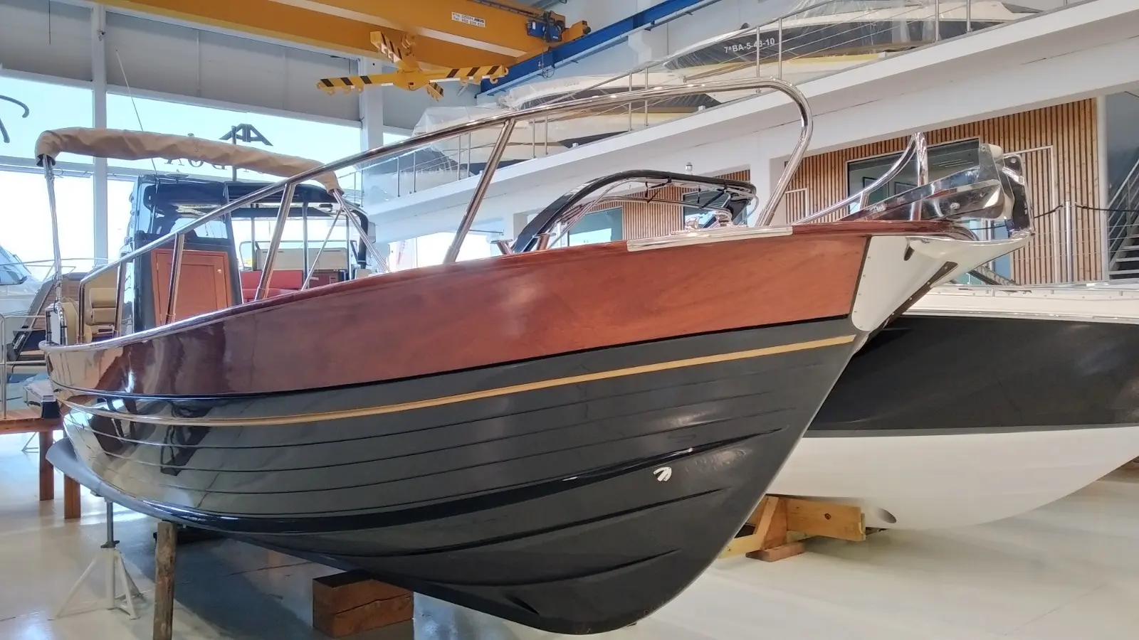 Positano 27 — Vue trois-quarts d’un bateau en bois exposé dans un hall nautique.