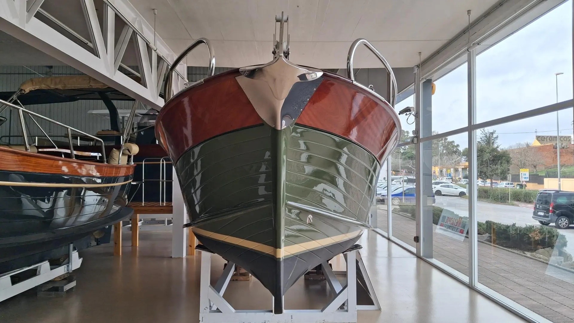 Positano 23 — Vue frontale d’un bateau exposé sur berceau dans un showroom vitré.