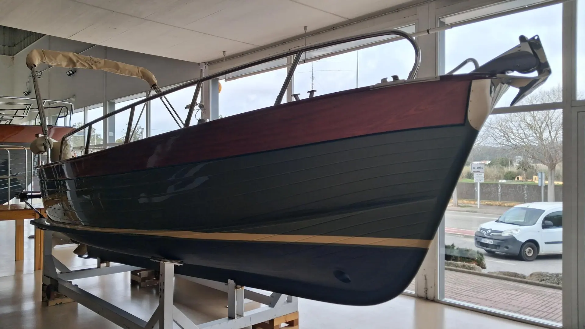 Positano 23 — Bateau à coque sombre exposé sur ber, vu de trois quarts dans un showroom.