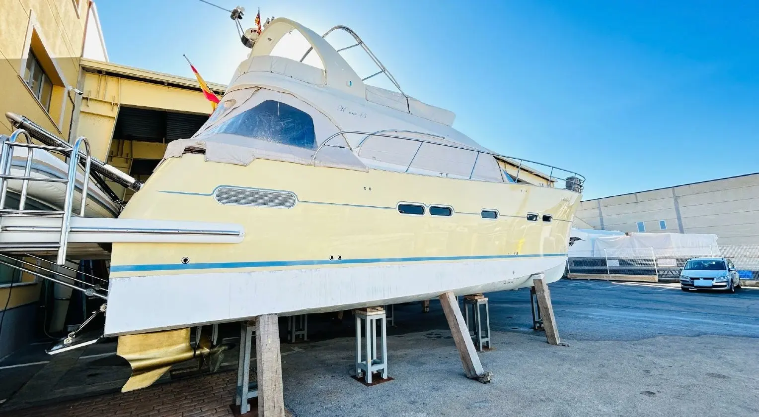 Galatzo K One 45 — Bateau à moteur blanc et jaune photographié à terre devant un bâtiment industriel.