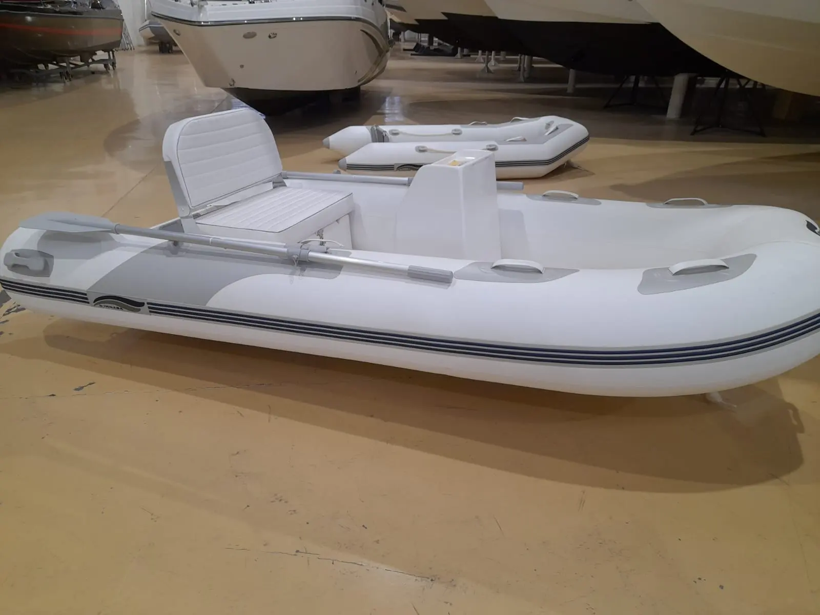 Imnasa 310 Rib — Bateau pneumatique blanc présenté dans un hall, vu de profil avec sa console et ses sièges.