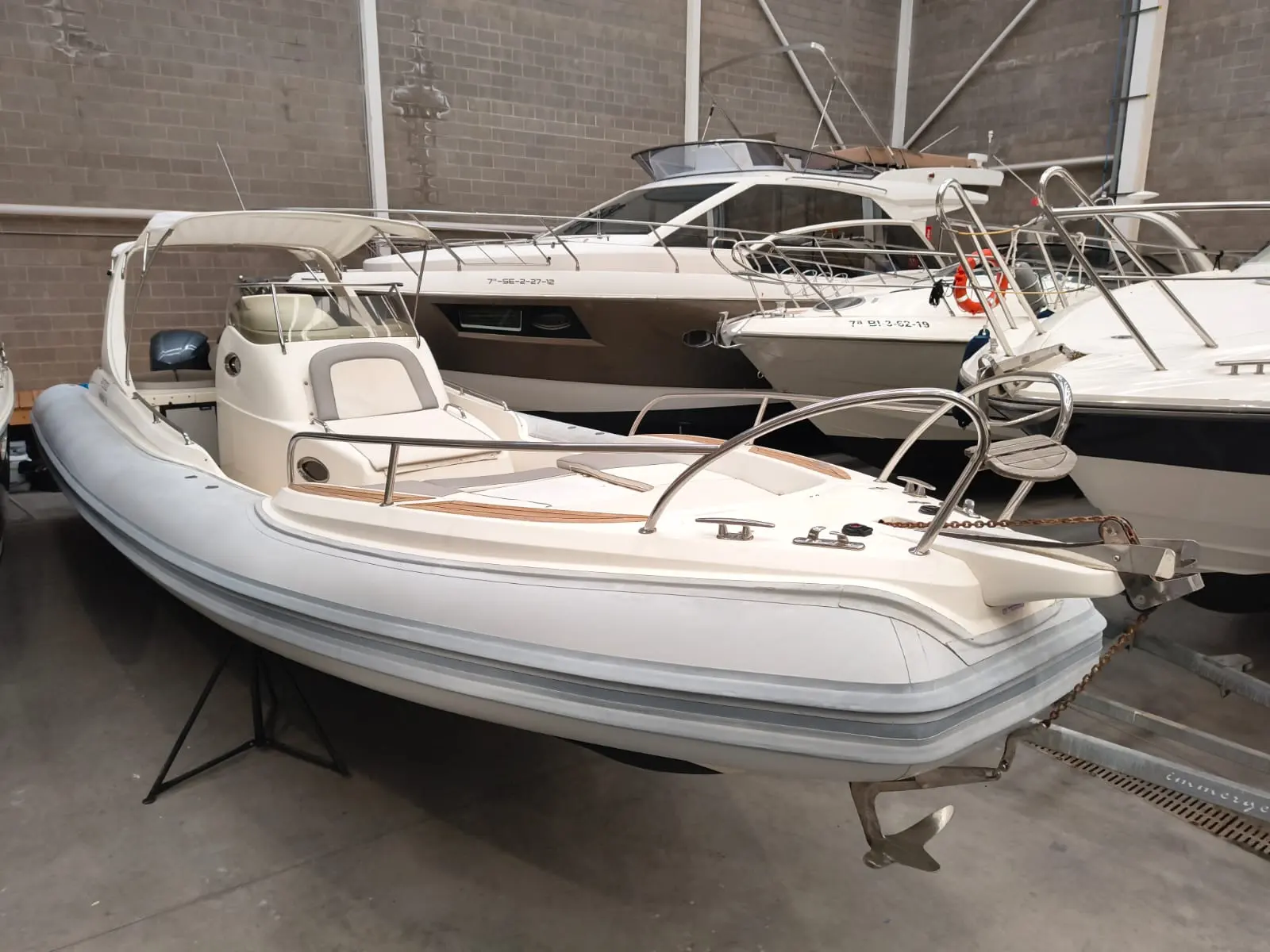 Lomac 1000 IN — Bateau semi-rigide blanc présenté en intérieur, entouré d'autres embarcations.
