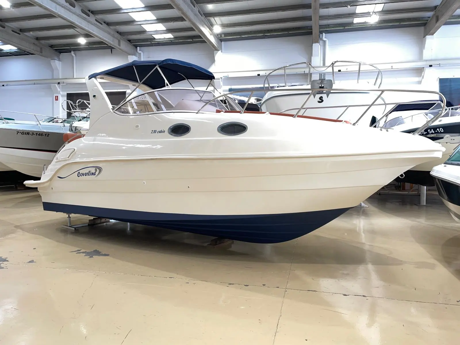 Coverline 710 Cabin — Bateau à cabine présenté de profil dans un hall couvert.