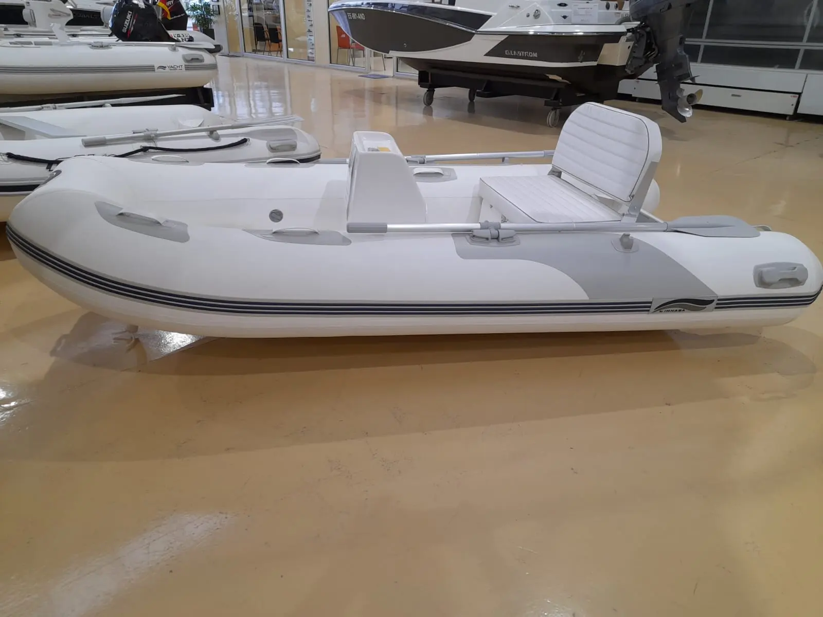 Imnasa 310 Rib — Semi-rigide blanc vu de profil dans un hall d’exposition.