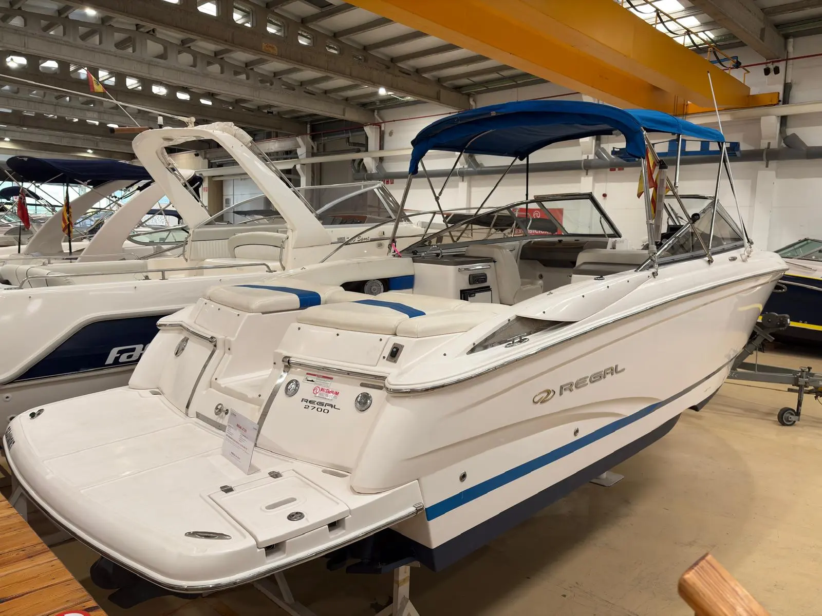 Regal 2700 — Bateau blanc et bleu présenté dans un hall, vu de trois quarts arrière.