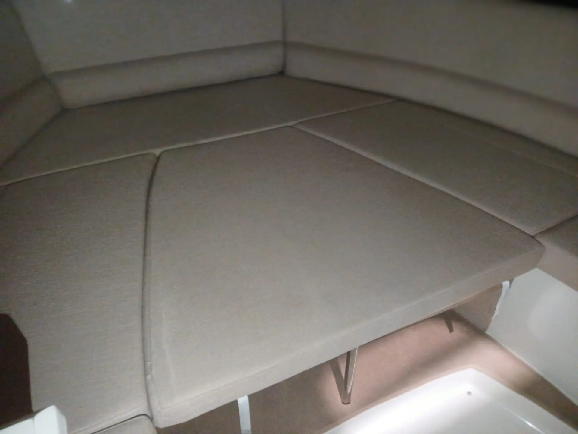 Scarani 30 Day Cruiser — Coussins beiges formant une couchette dans l'intérieur du bateau.