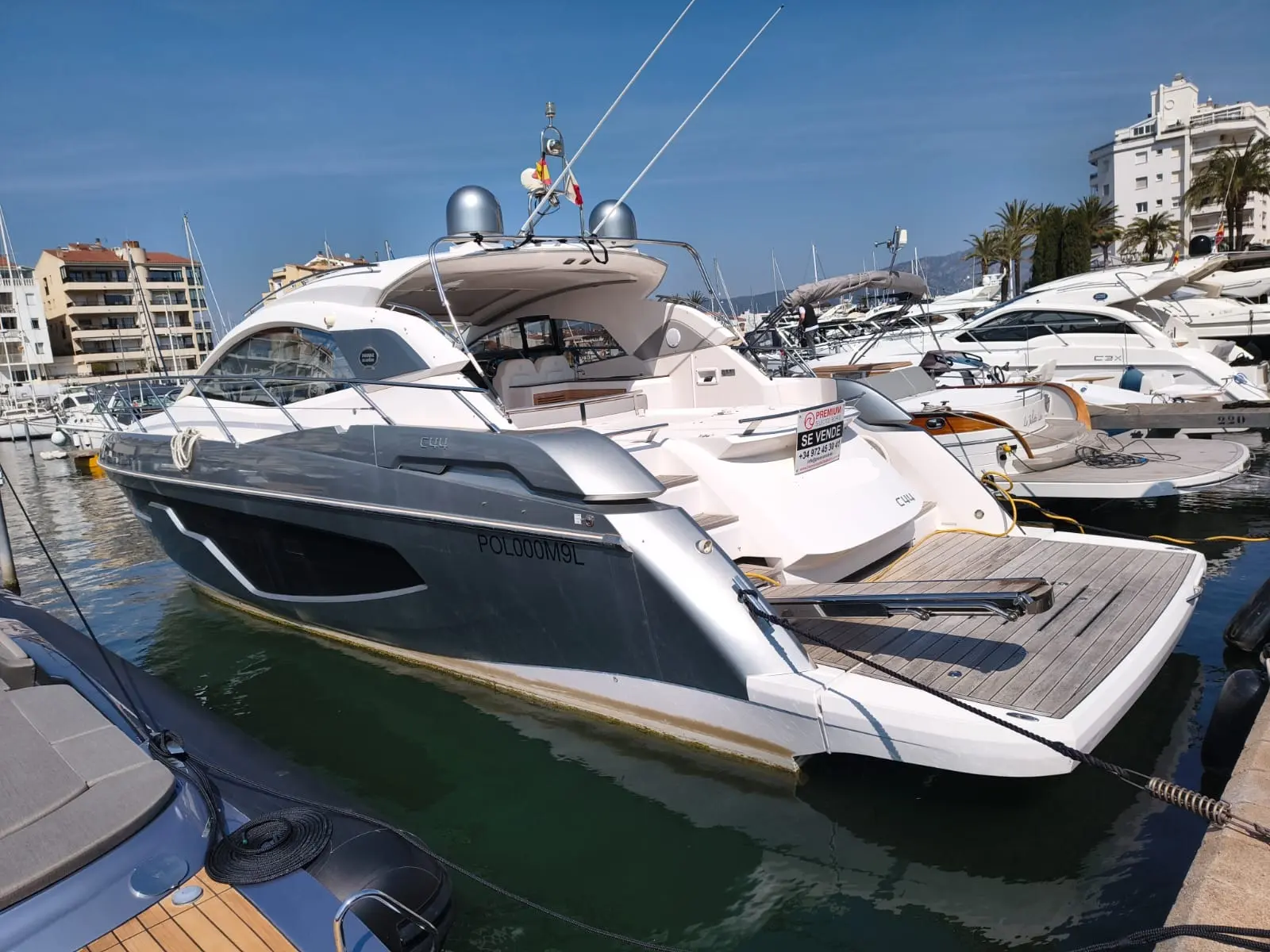 Sessa Marine C44 — Bateau à moteur blanc et gris amarré dans une marina, vu de trois quarts arrière.