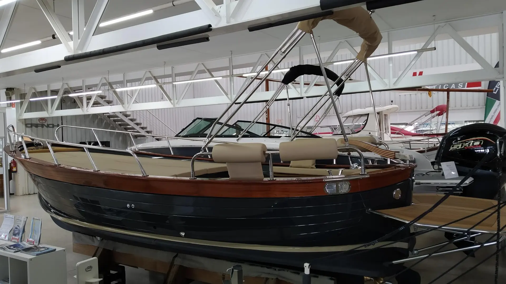 Positano 27 — Bateau à moteur exposé en intérieur, avec sièges et taud beige.