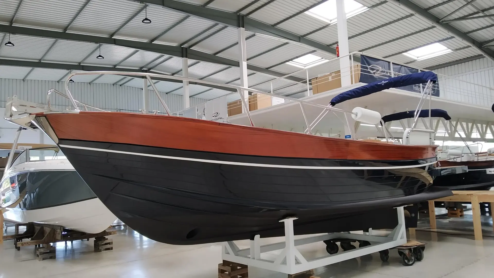 Positano 27 — Bateau à coque noire et pont en bois exposé dans un hangar.