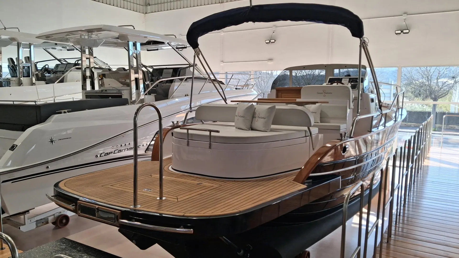 Gozzo Positano 28 Sole — Vue arrière trois-quarts d’un bateau à moteur exposé dans un showroom nautique.