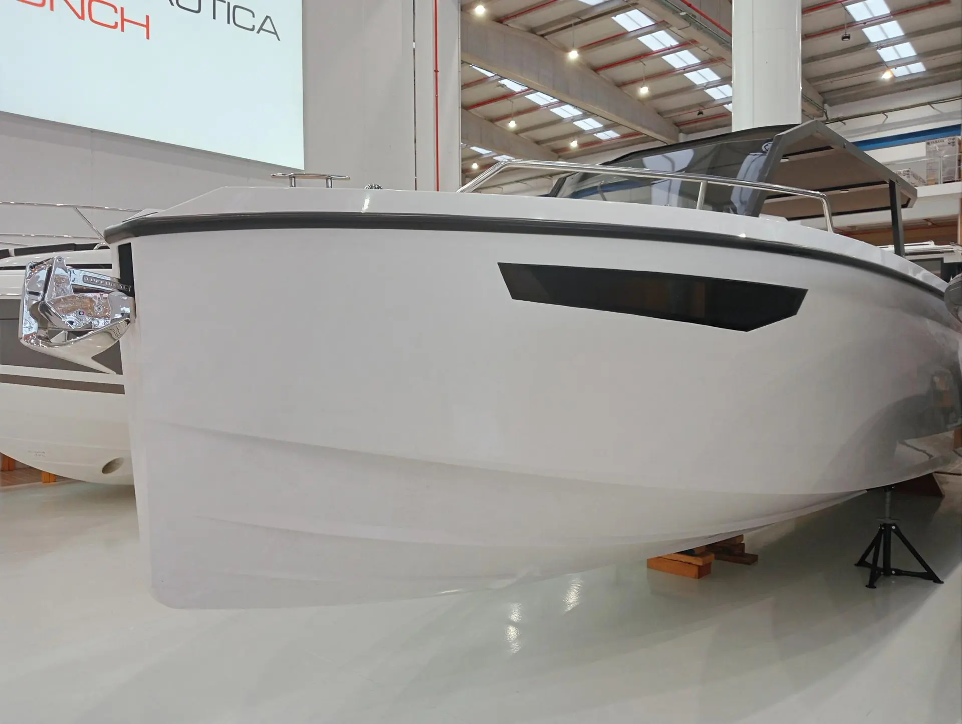 Rand Boats Archipelago 32 — Vue rapprochée de l’étrave et du flanc d’un bateau blanc exposé en intérieur.