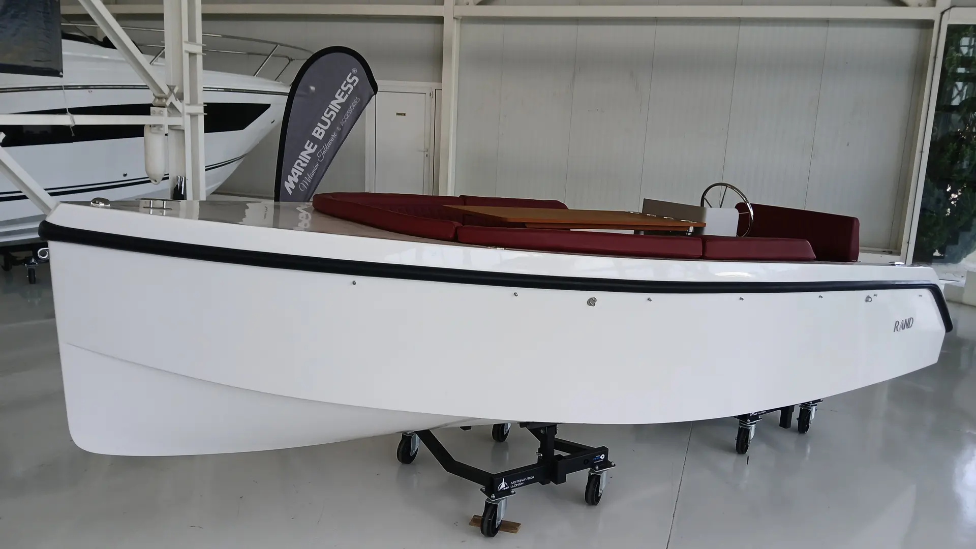 Rand Boats Picnic 18 — Vue latérale d’un bateau blanc sur berceau, exposé dans un hangar.