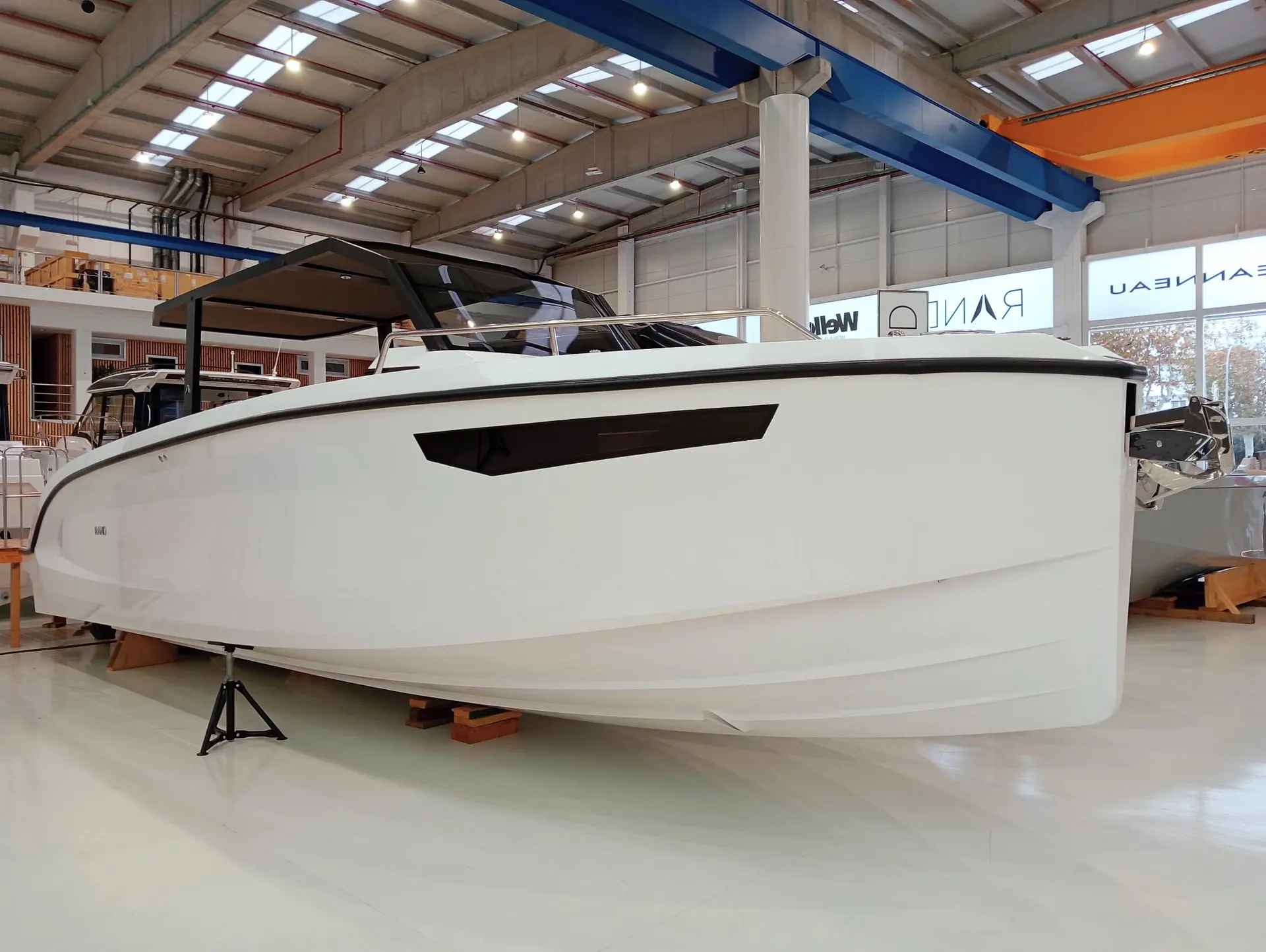 Rand Boats Archipelago 32 — Bateau blanc exposé sur des supports dans un hall couvert.
