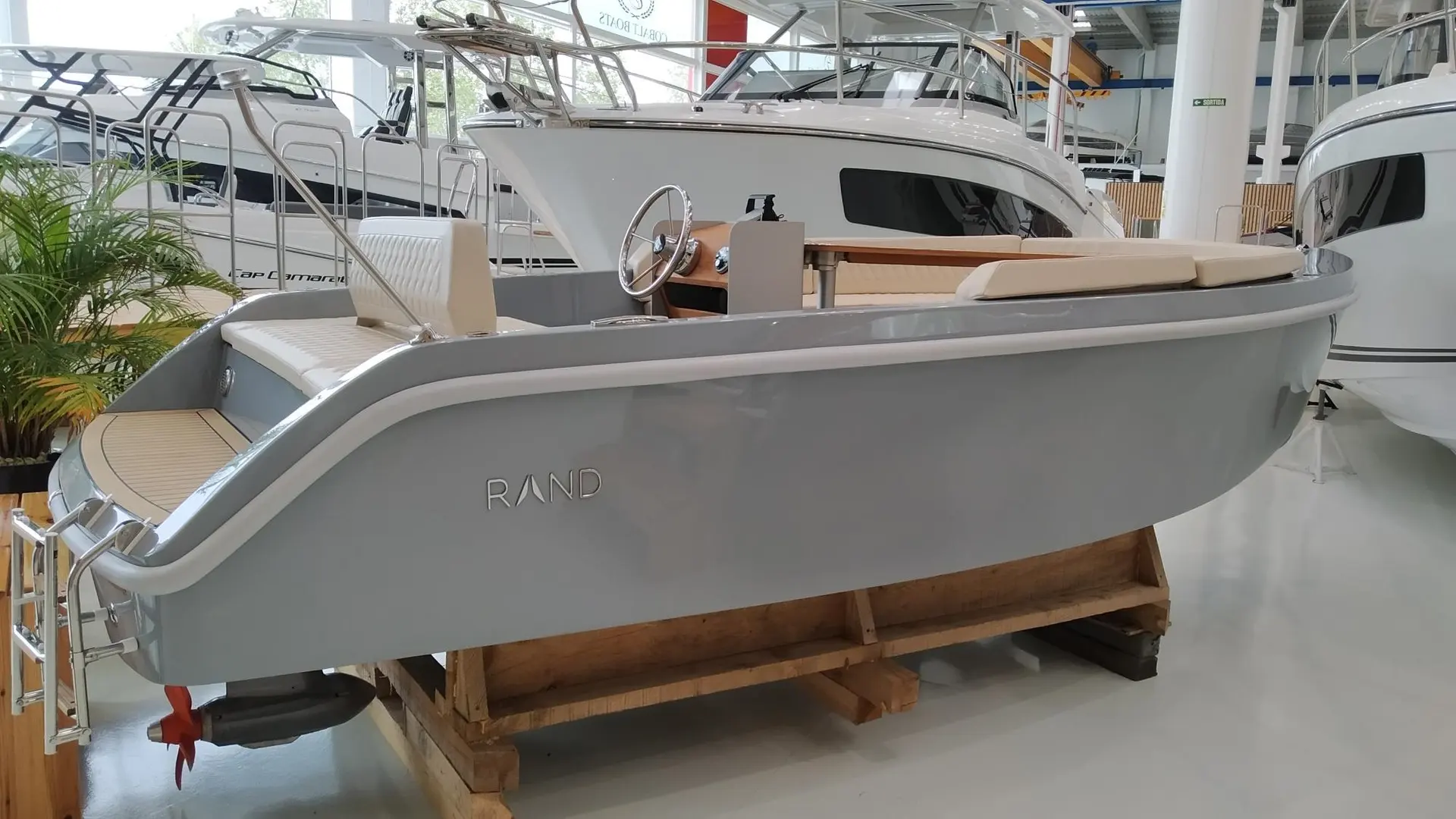 Rand Boats Picnic 18 — Bateau gris présenté sur berceau dans un showroom, vu de trois quarts arrière.