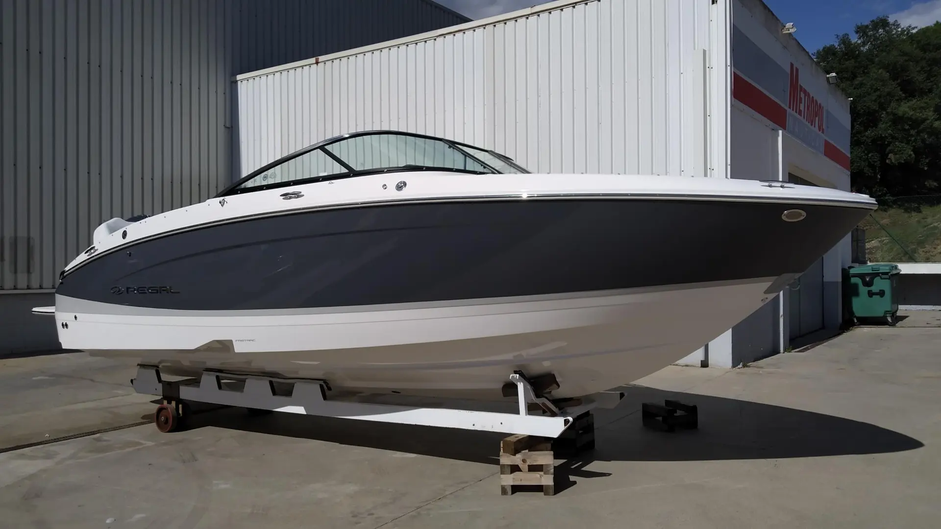 Regal LX4 — Bateau à moteur blanc et noir posé sur une remorque devant un bâtiment.