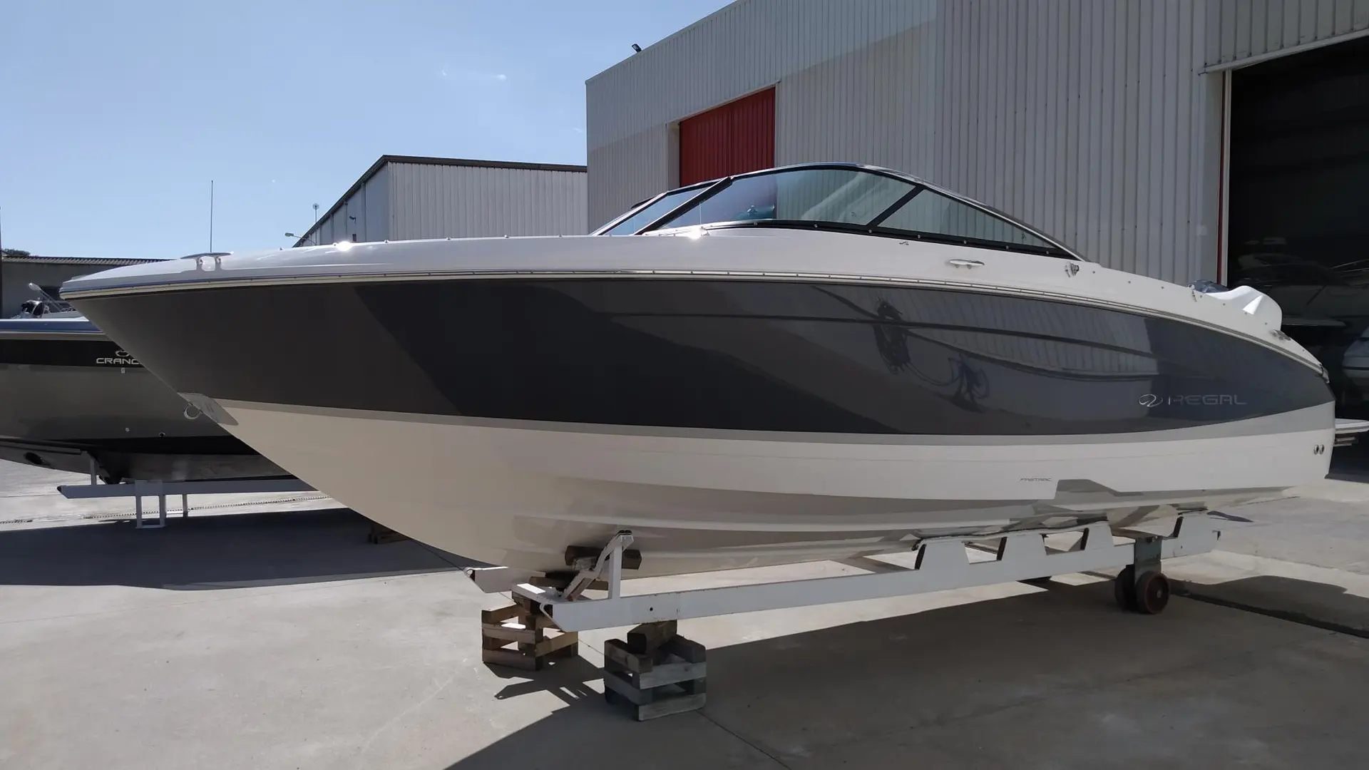 Regal LX4 — Bateau à moteur blanc et gris présenté sur sa remorque devant un hangar.