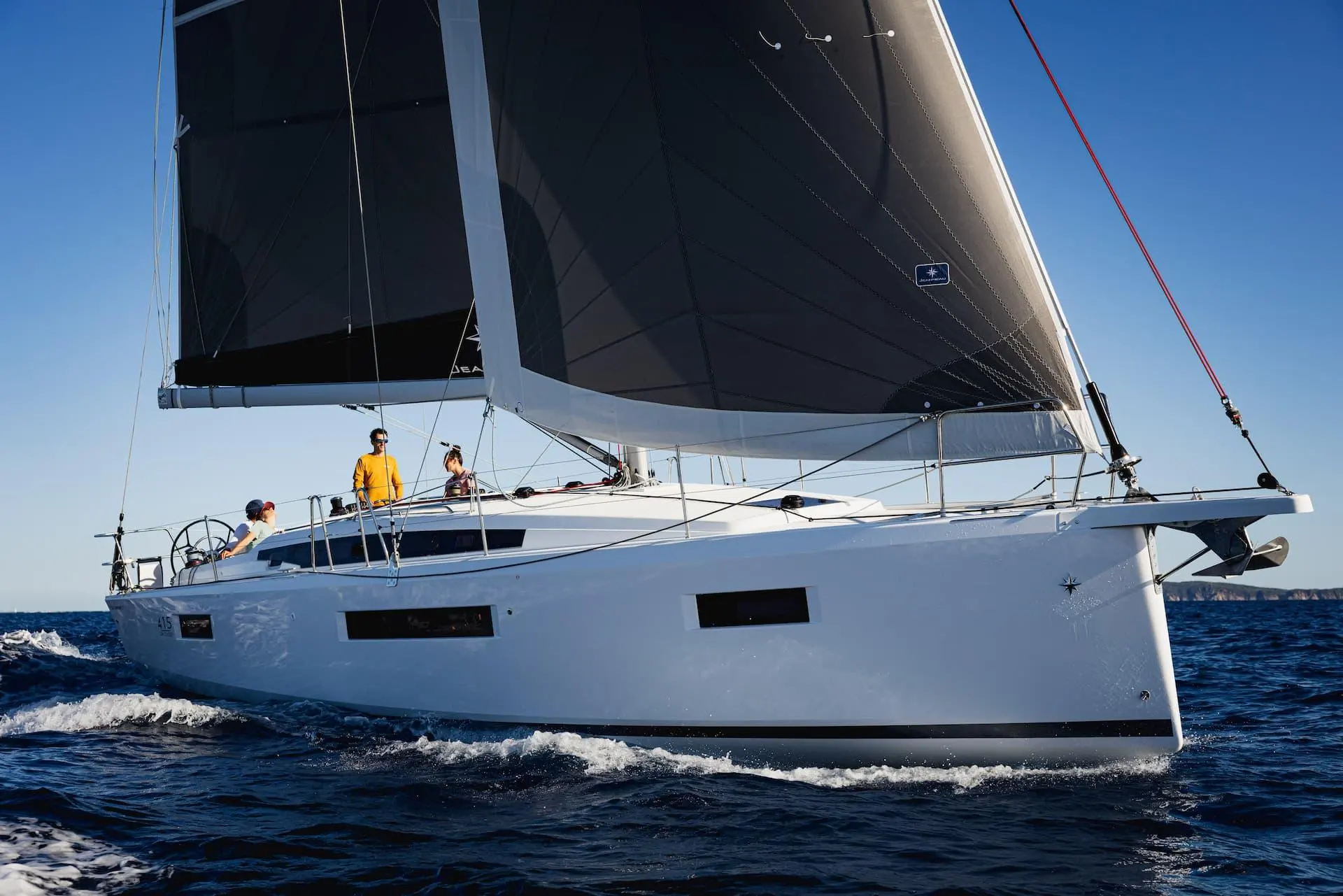 Jeanneau Sun Odyssey 415 — Voilier blanc à deux voiles naviguant au large, avec trois personnes sur le pont.