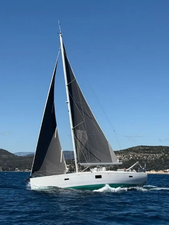 Hanse 455 — Voilier blanc naviguant sous voiles près d'une côte méditerranéenne.