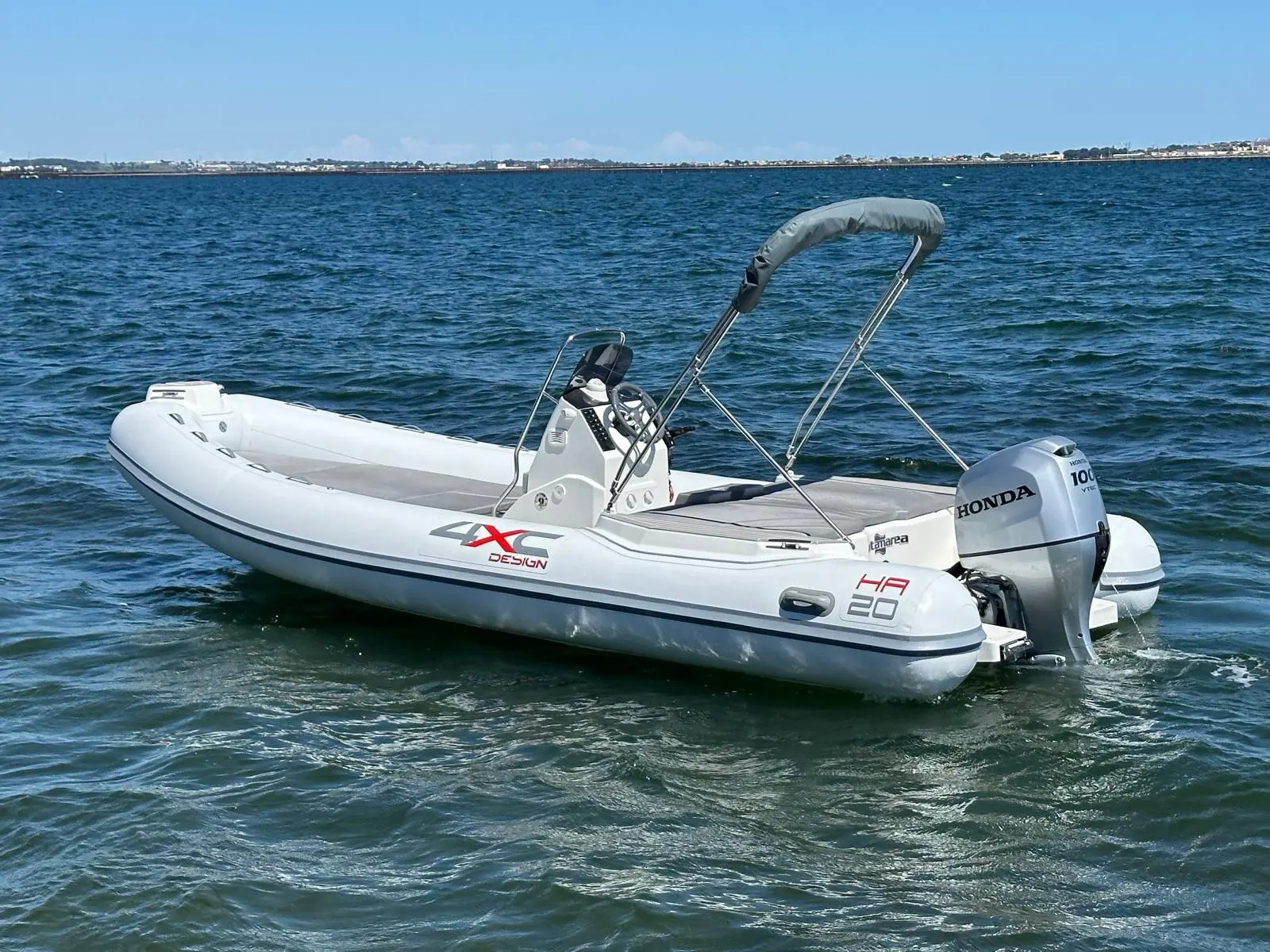 4XC HA20 — Bateau pneumatique blanc équipé d’un moteur hors-bord, photographié sur l’eau.