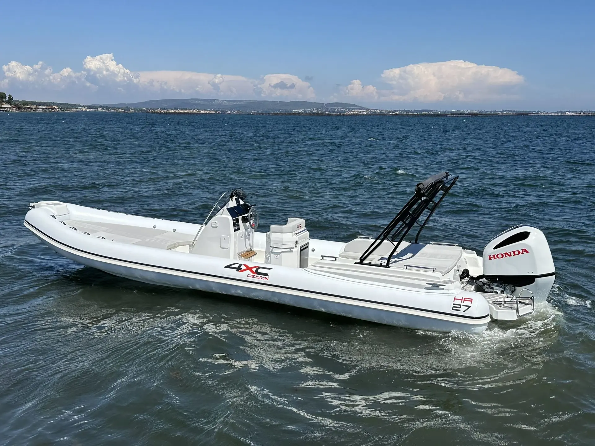 4XC HA27 — Bateau pneumatique blanc équipé d’un moteur hors-bord, naviguant près du rivage.